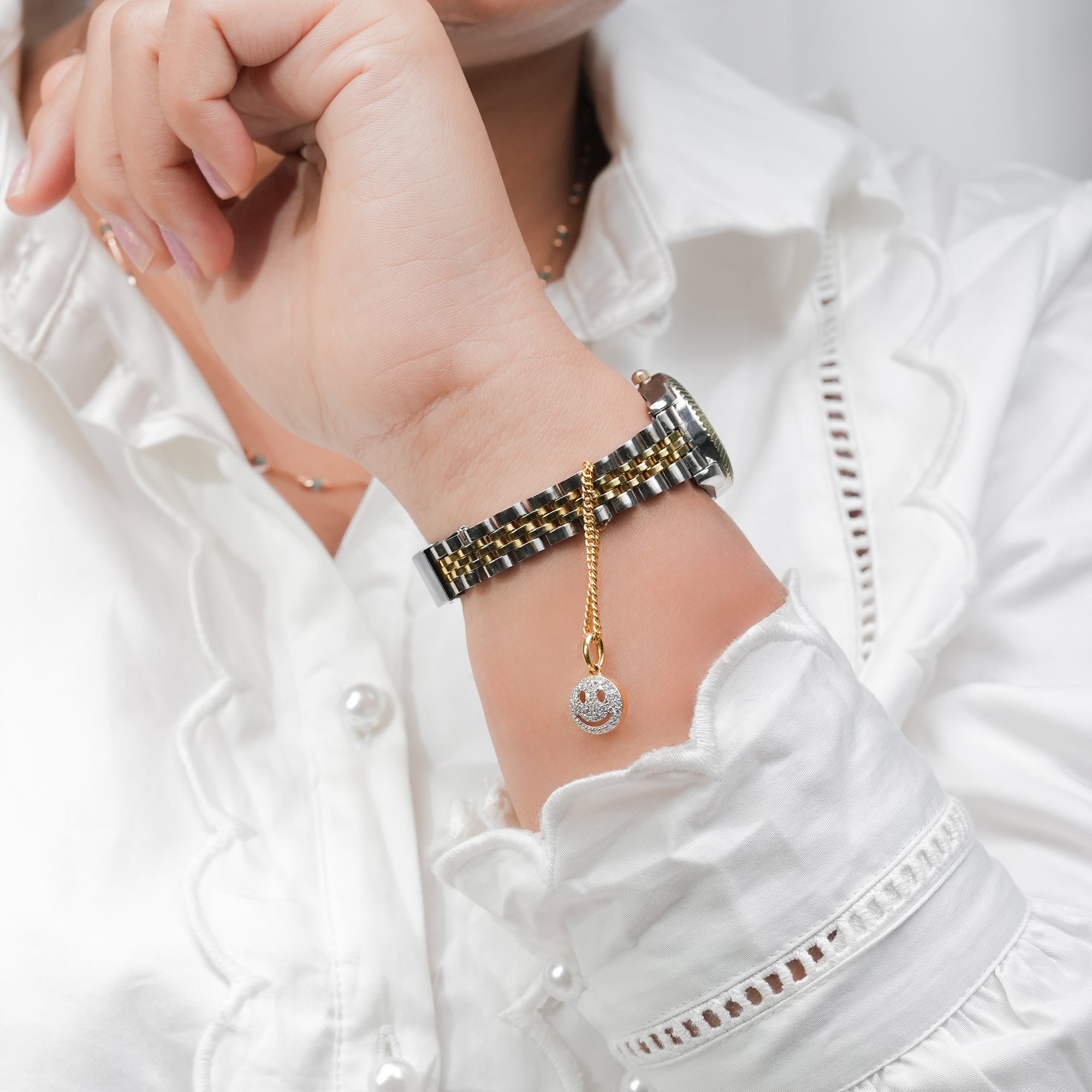 A stylish two-tone watch with a gold chain accent and a diamond smiley face pendant, blending fun charm with luxury appeal.