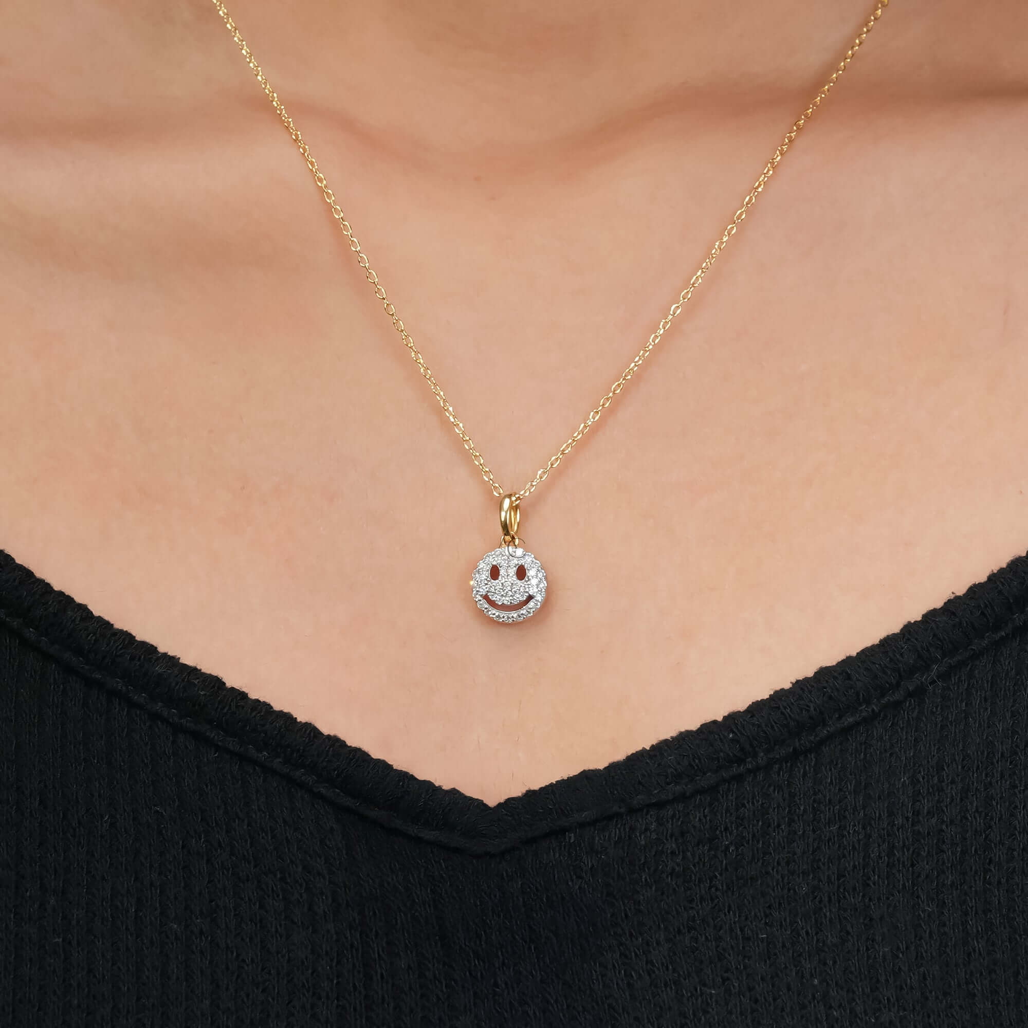 Gold smiley face pendant necklace with diamond detailing, shown on a polished and refined look.
