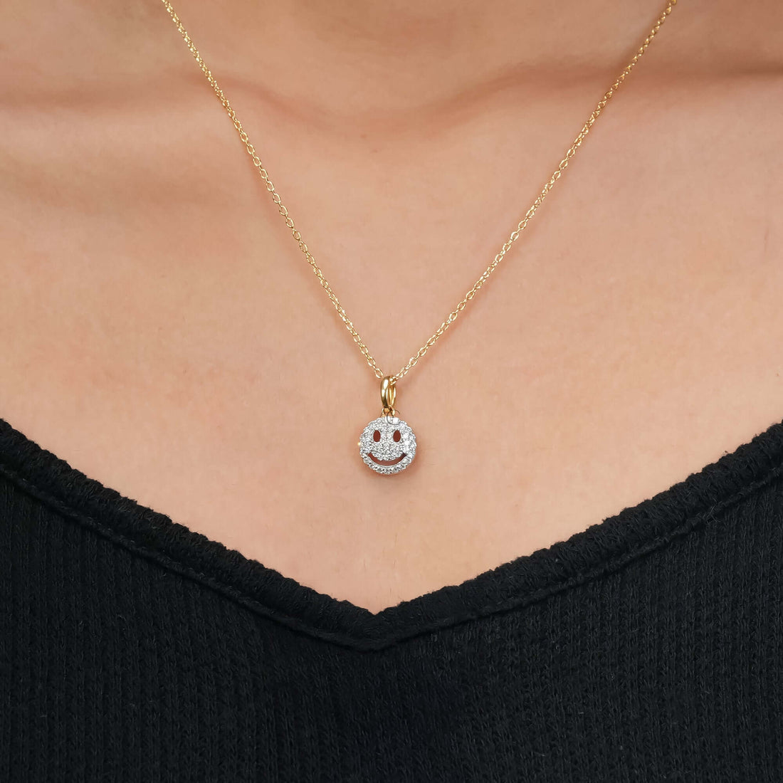 Gold smiley face pendant necklace with diamond detailing, shown on a polished and refined look.