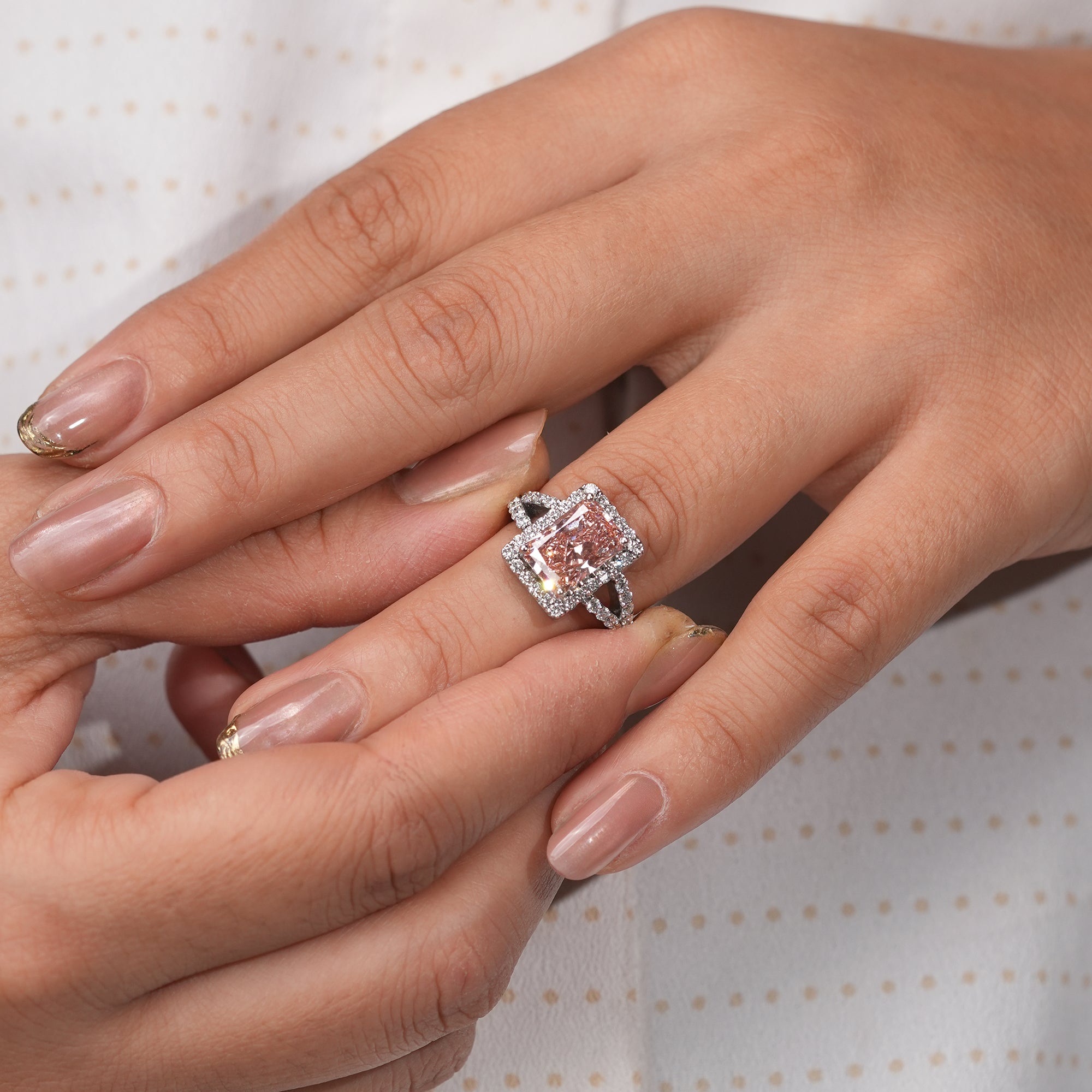 A stunning pink diamond ring glowing with elegance, framed by shimmering white diamonds on a sleek split band.