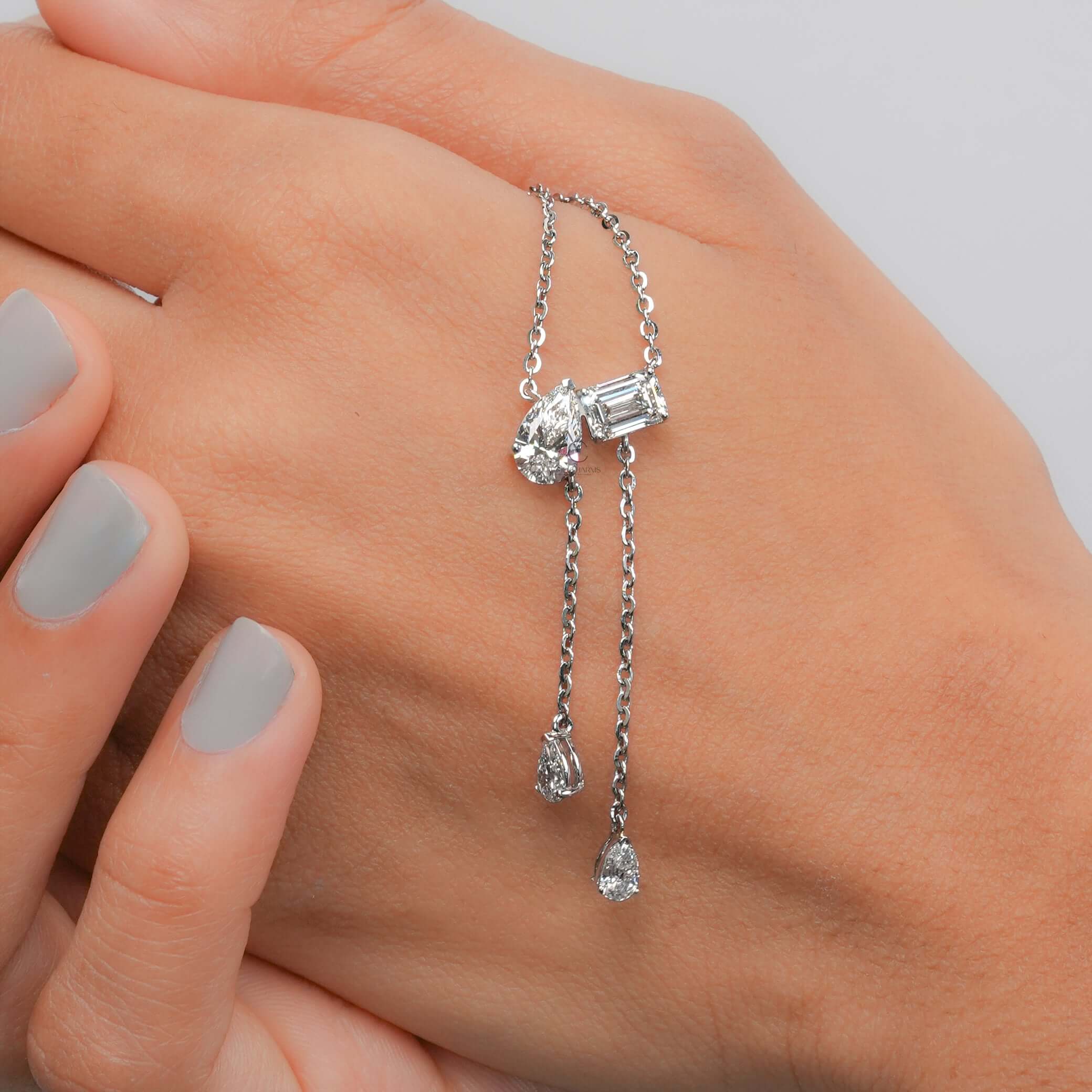 Elegant lab grown diamond Toi et Moi pendant necklace, featuring Emerald and Pear Cuts, worn gracefully on hand.