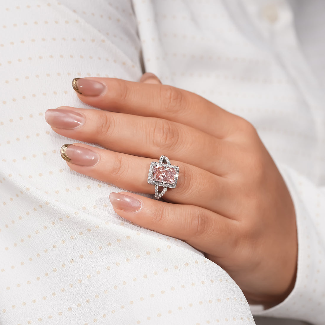 Luxury pink diamond engagement ring featuring a radiant-cut stone encircled by white diamonds on a platinum split band.
