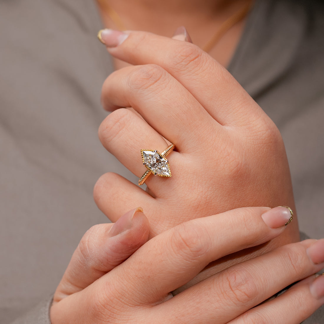 Fine jewelry marquise diamond ring with gold milgrain border and polished gold band.