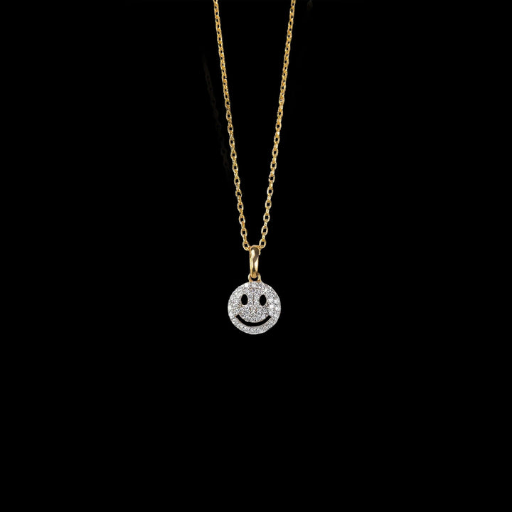 A gold necklace with a sparkling smiley face pendant, combining luxury and joy in a stylish, diamond-studded design.