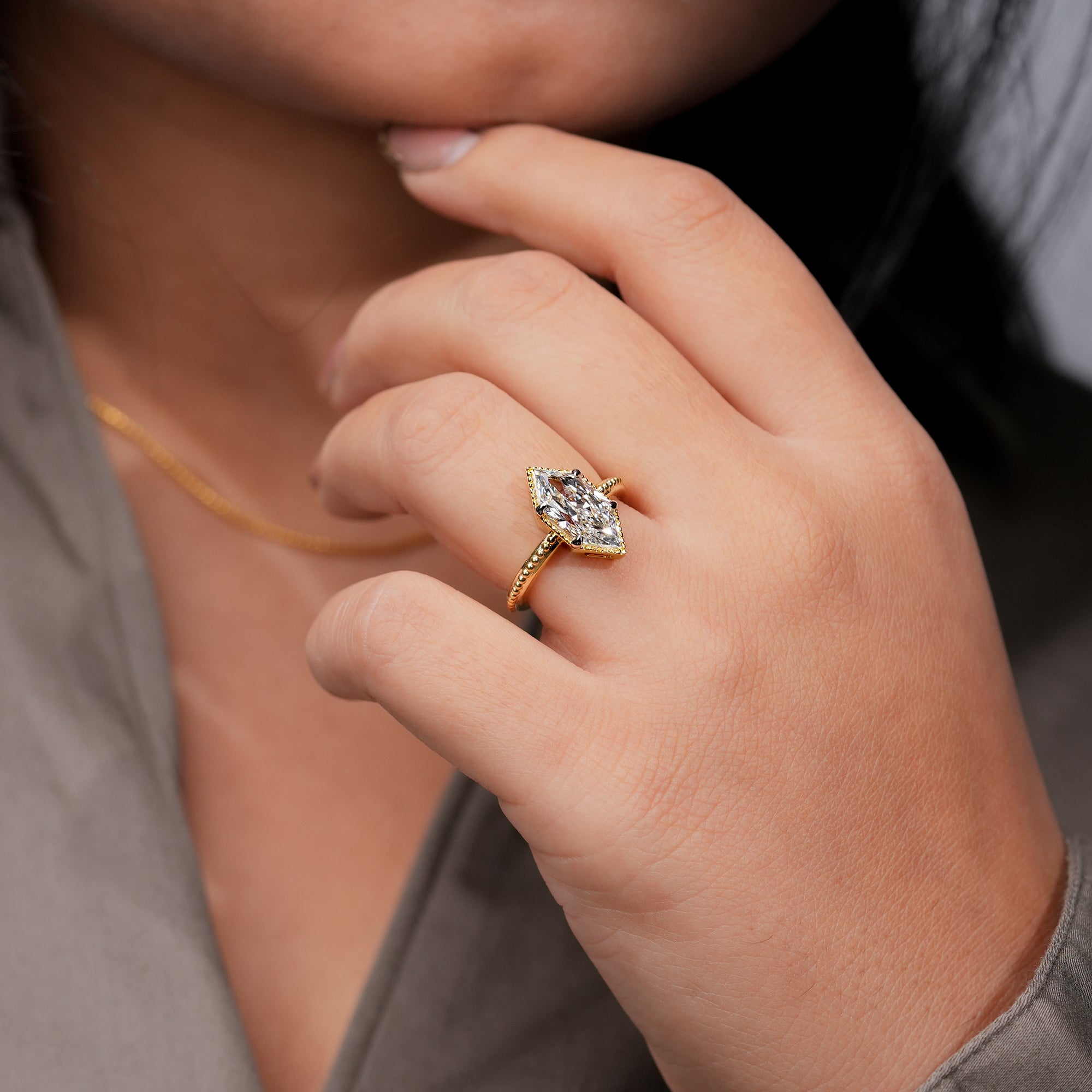 Yellow gold marquise diamond engagement ring with milgrain bezel setting.