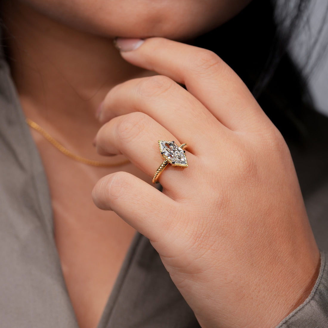 Yellow gold marquise diamond engagement ring with milgrain bezel setting.