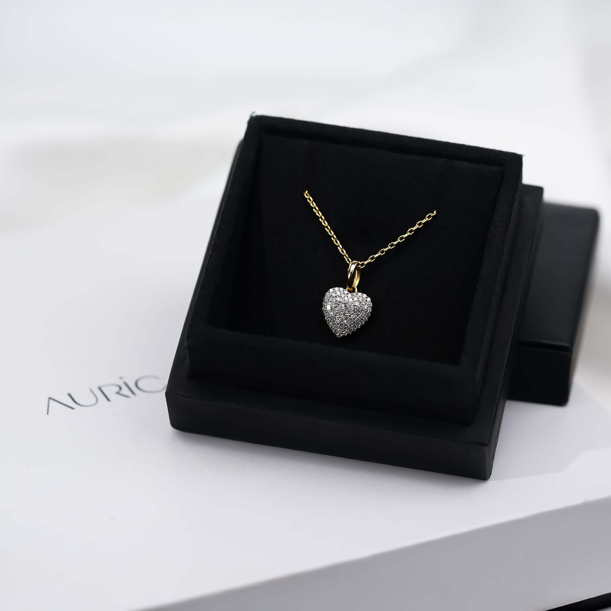 A shimmering diamond heart pendant hangs from a delicate gold chain, reflecting timeless love and refined elegance.