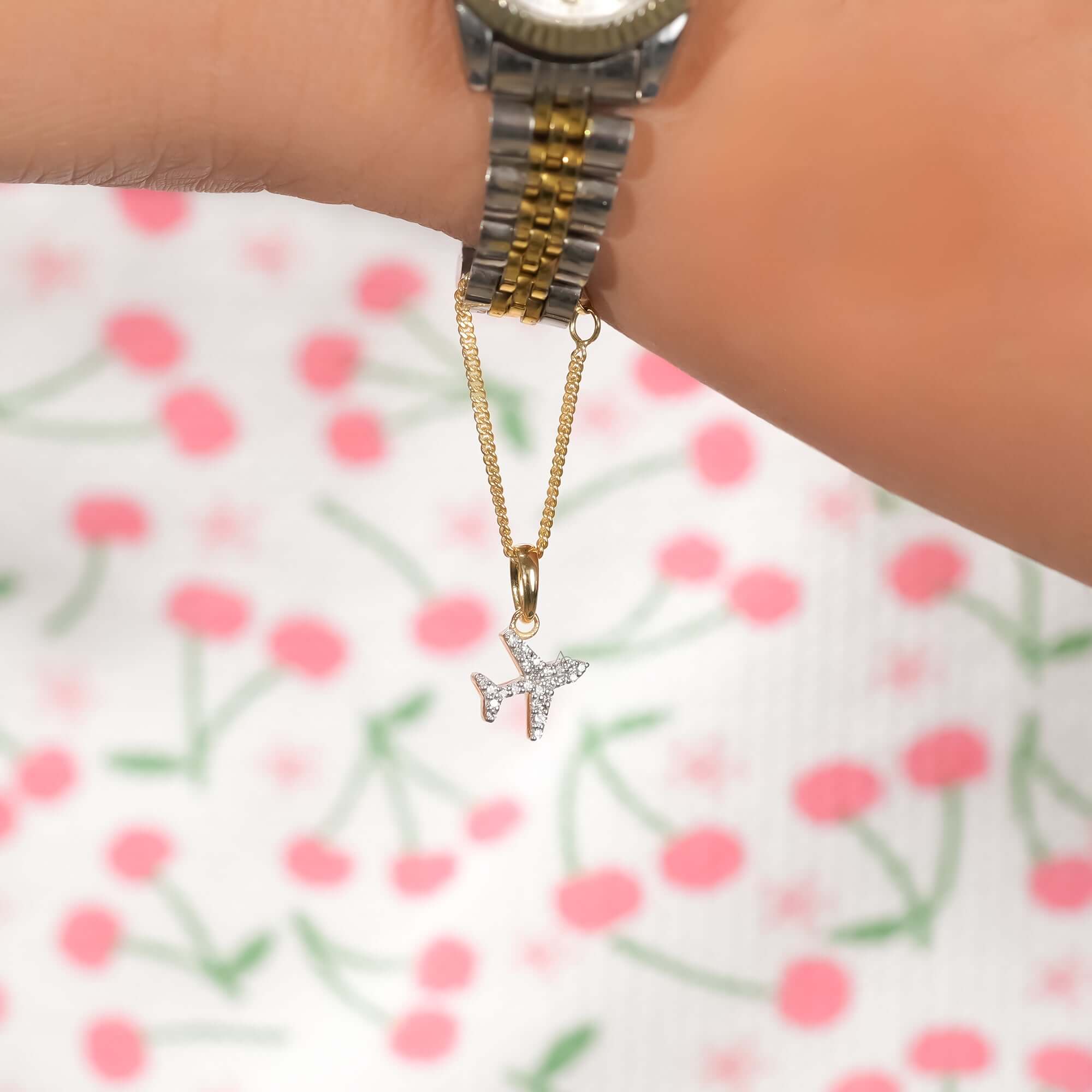 Two-tone bracelet watch with a gold chain accent and a diamond-studded airplane charm, shown on wrist for a refined and fashionable look.