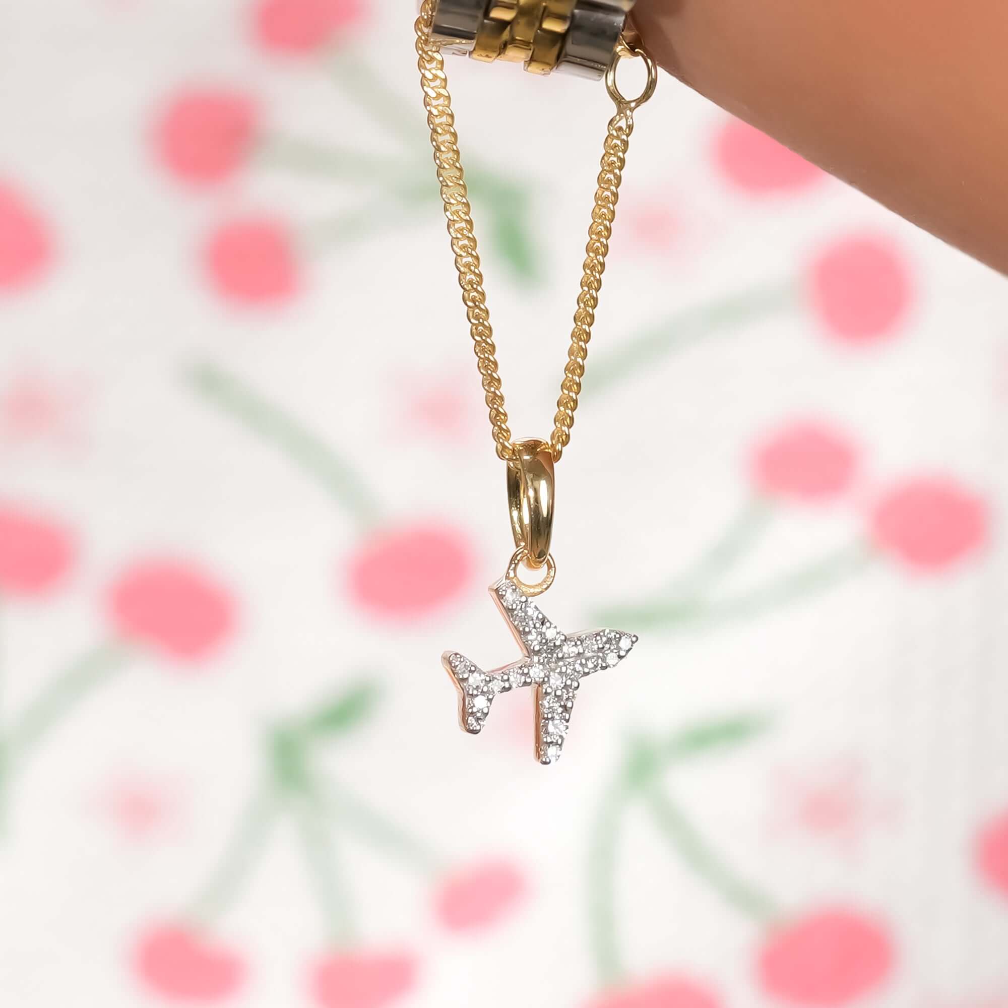 Gold and silver wristwatch with a gold chain and airplane pendant charm encrusted with diamonds a modern, travel-inspired jewelry accessory.
