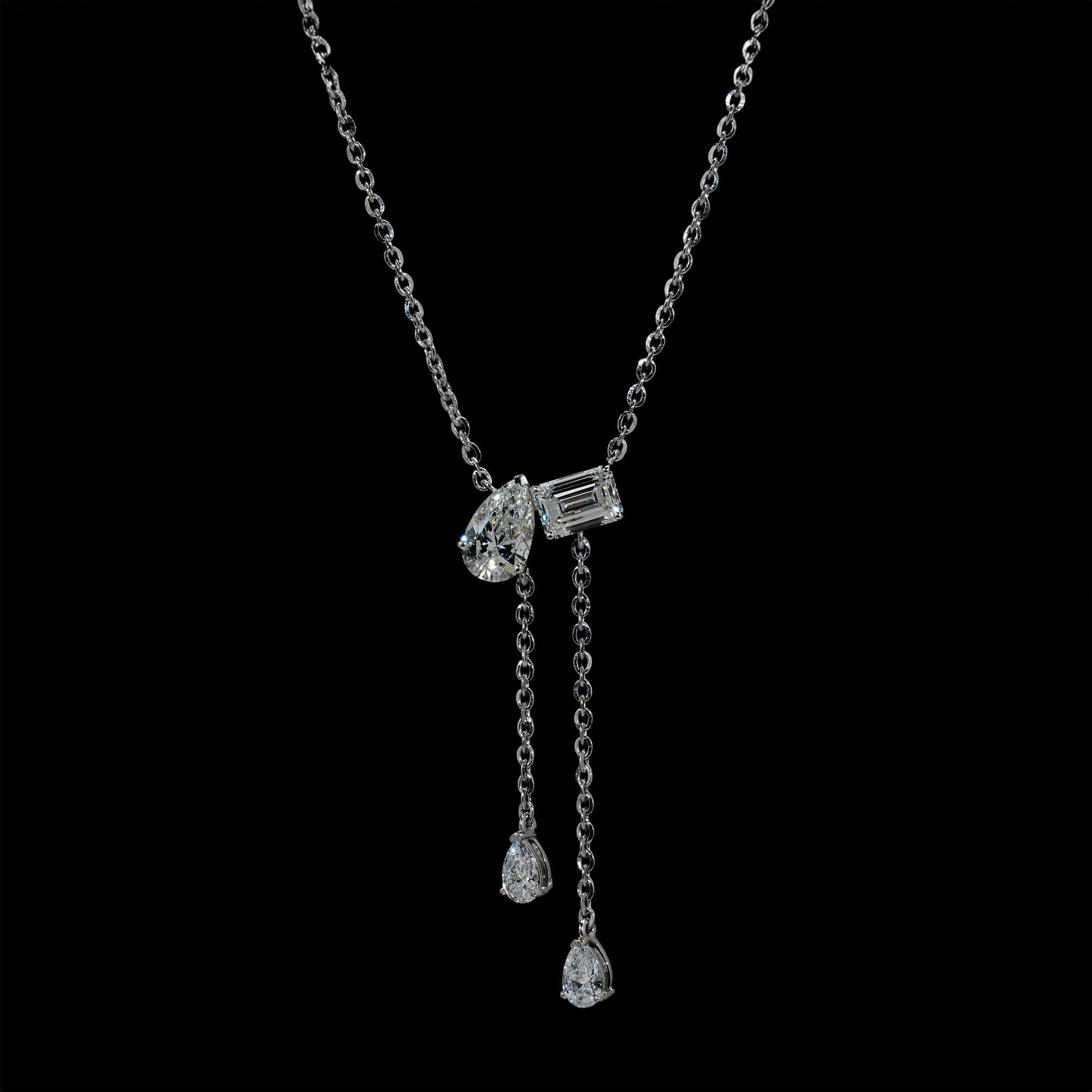 A luxury lab-grown diamond lariat necklace featuring an Emerald and Pear Cut pendant, elegantly worn on the neck.