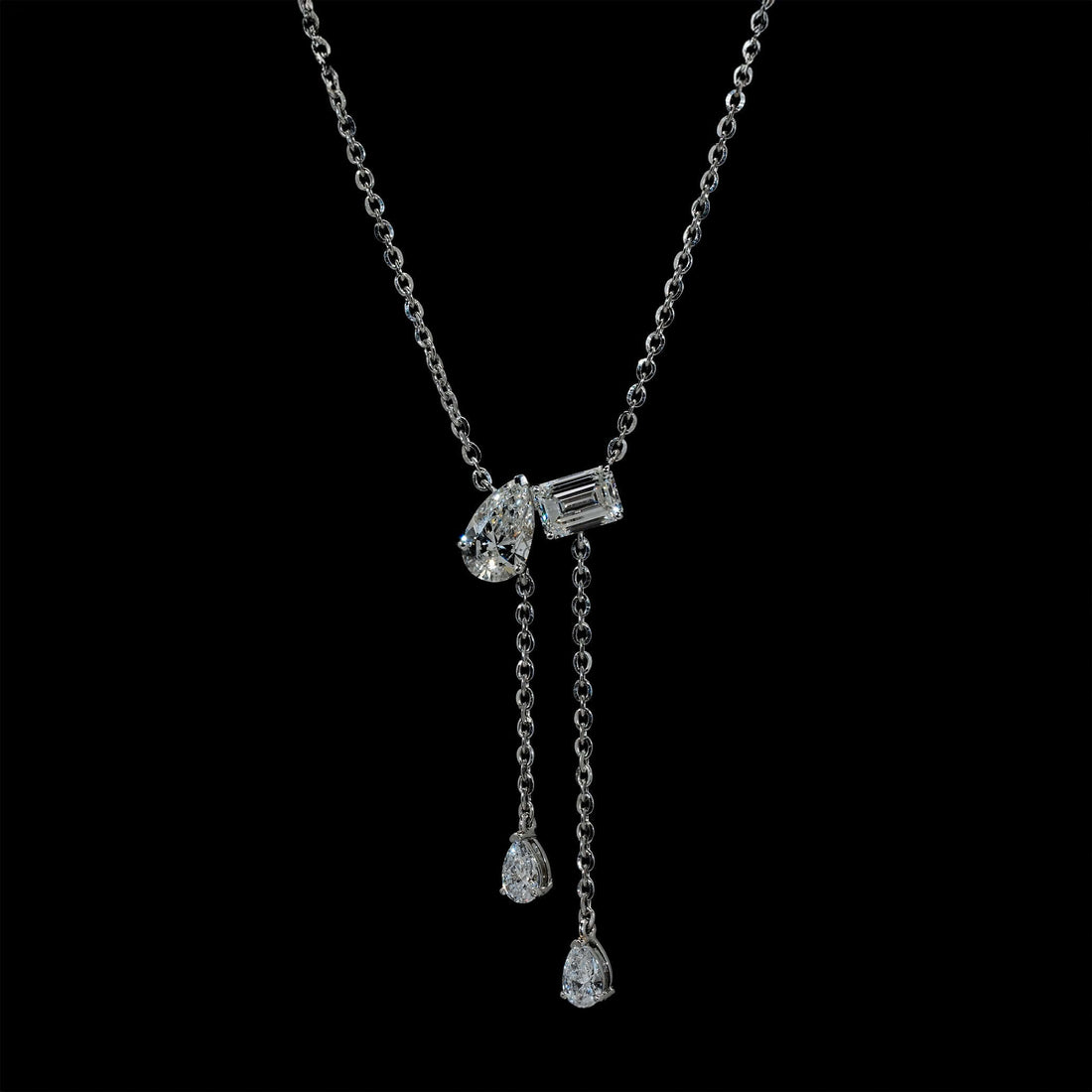 A luxury lab-grown diamond lariat necklace featuring an Emerald and Pear Cut pendant, elegantly worn on the neck.