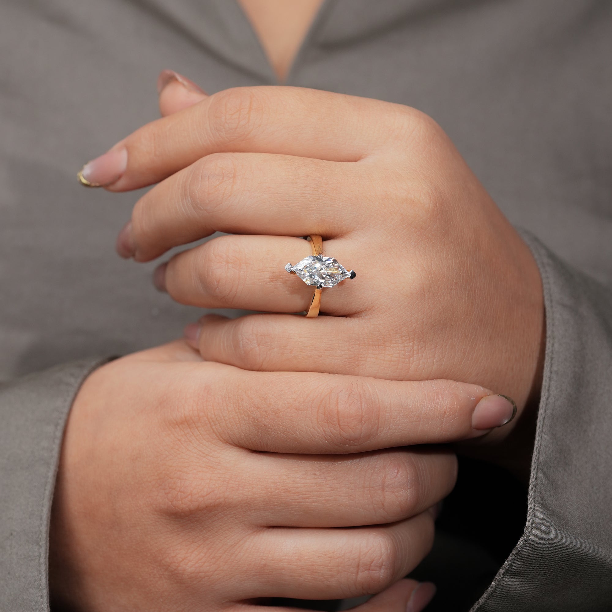 An exquisite yellow gold ring centered with a marquise-cut diamond that catches the light beautifully, highlighting the clean, modern design of the smooth band.