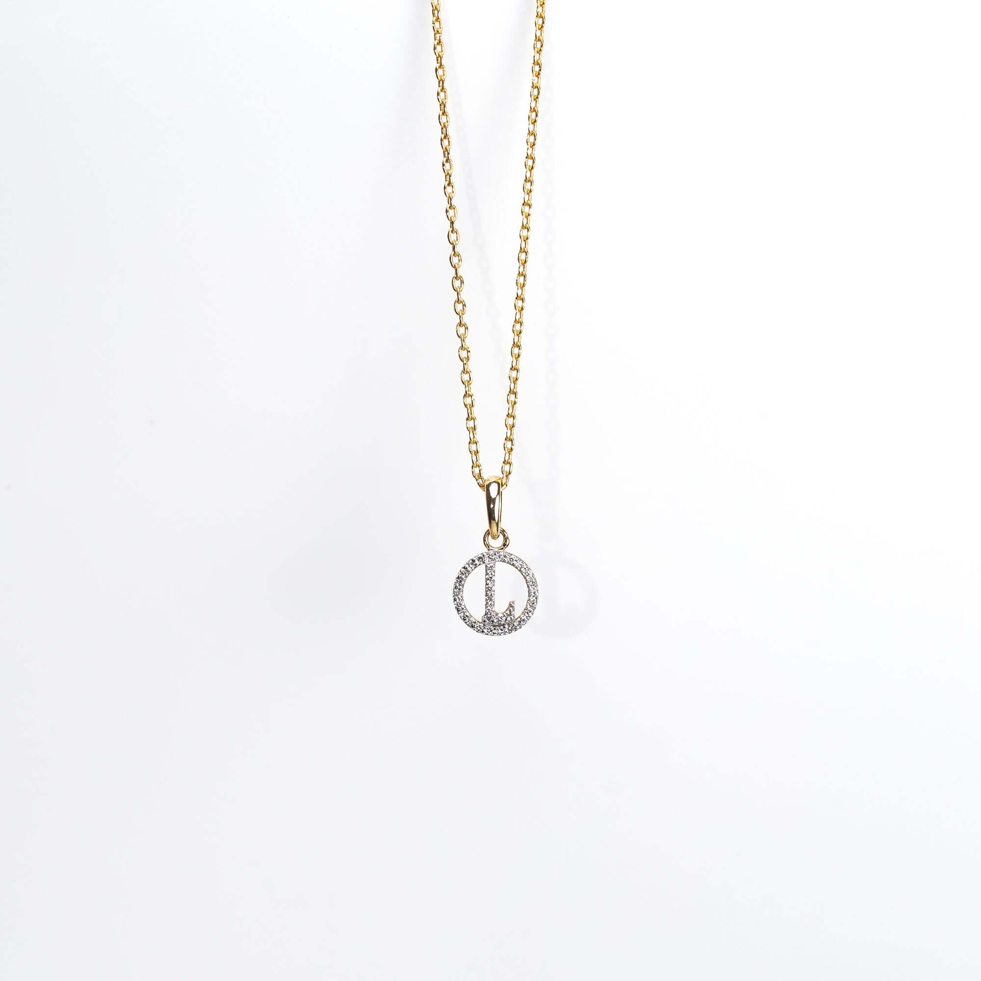 A delicate gold necklace with a round diamond-studded pendant, showcasing a refined and contemporary style.