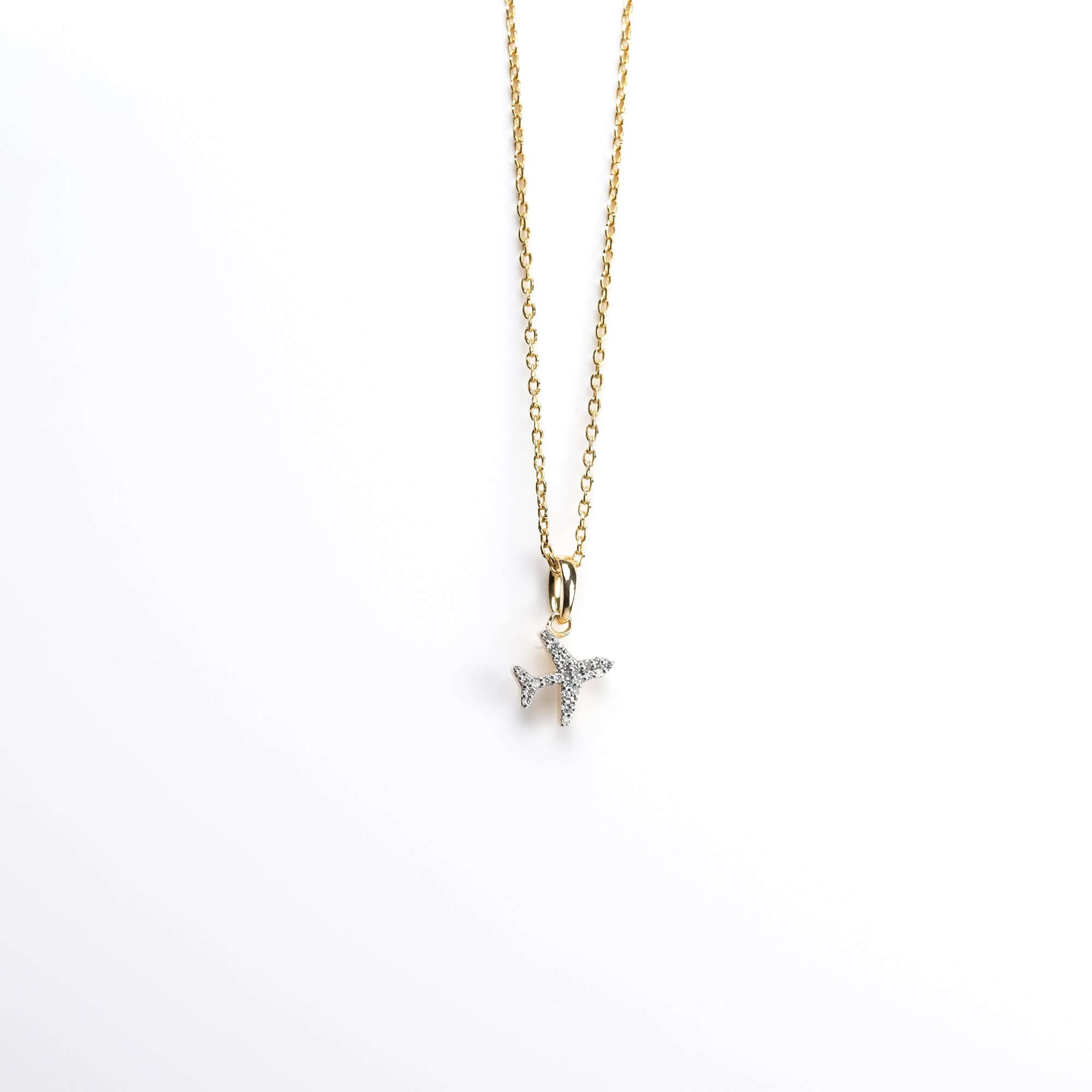 Gold airplane pendant necklace with pavé diamonds, presented on a white background for a sophisticated and timeless appeal.