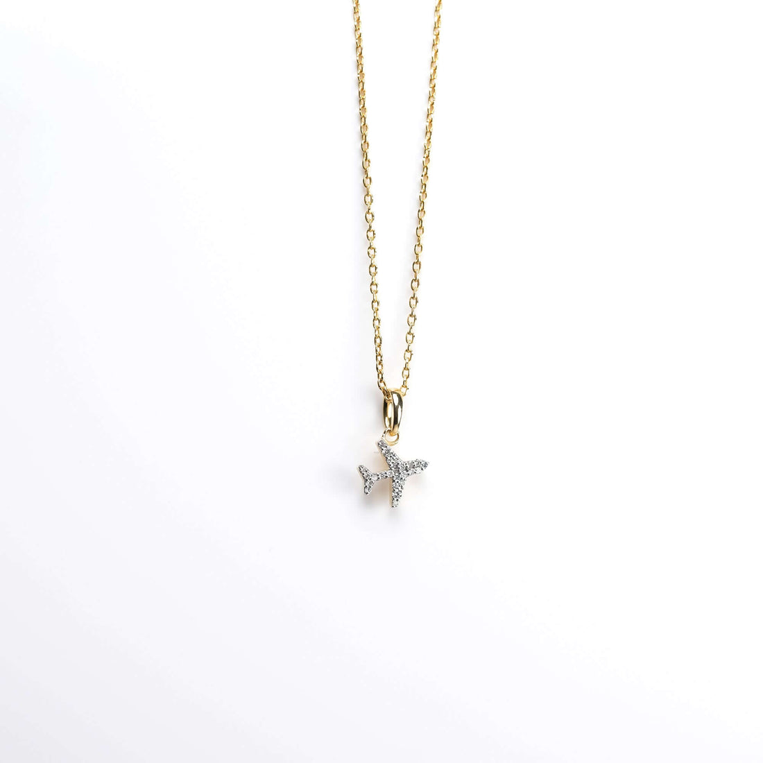 Gold airplane pendant necklace with pavé diamonds, presented on a white background for a sophisticated and timeless appeal.
