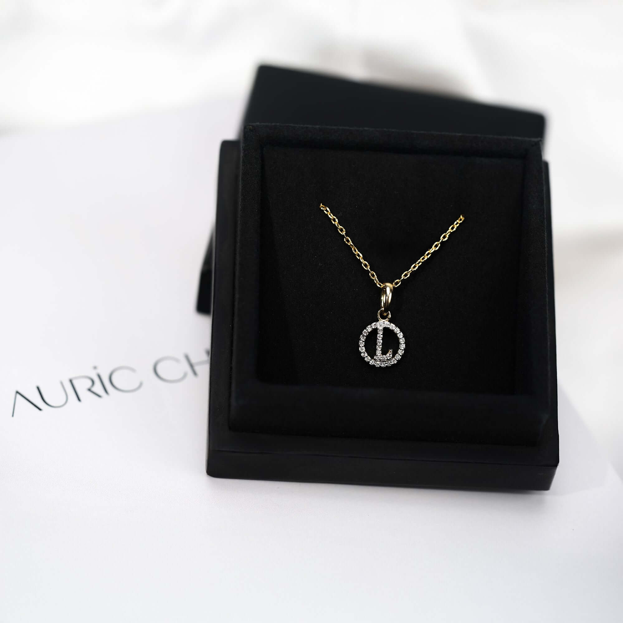 Gold pendant necklace with a circular diamond design, with L letter pendant