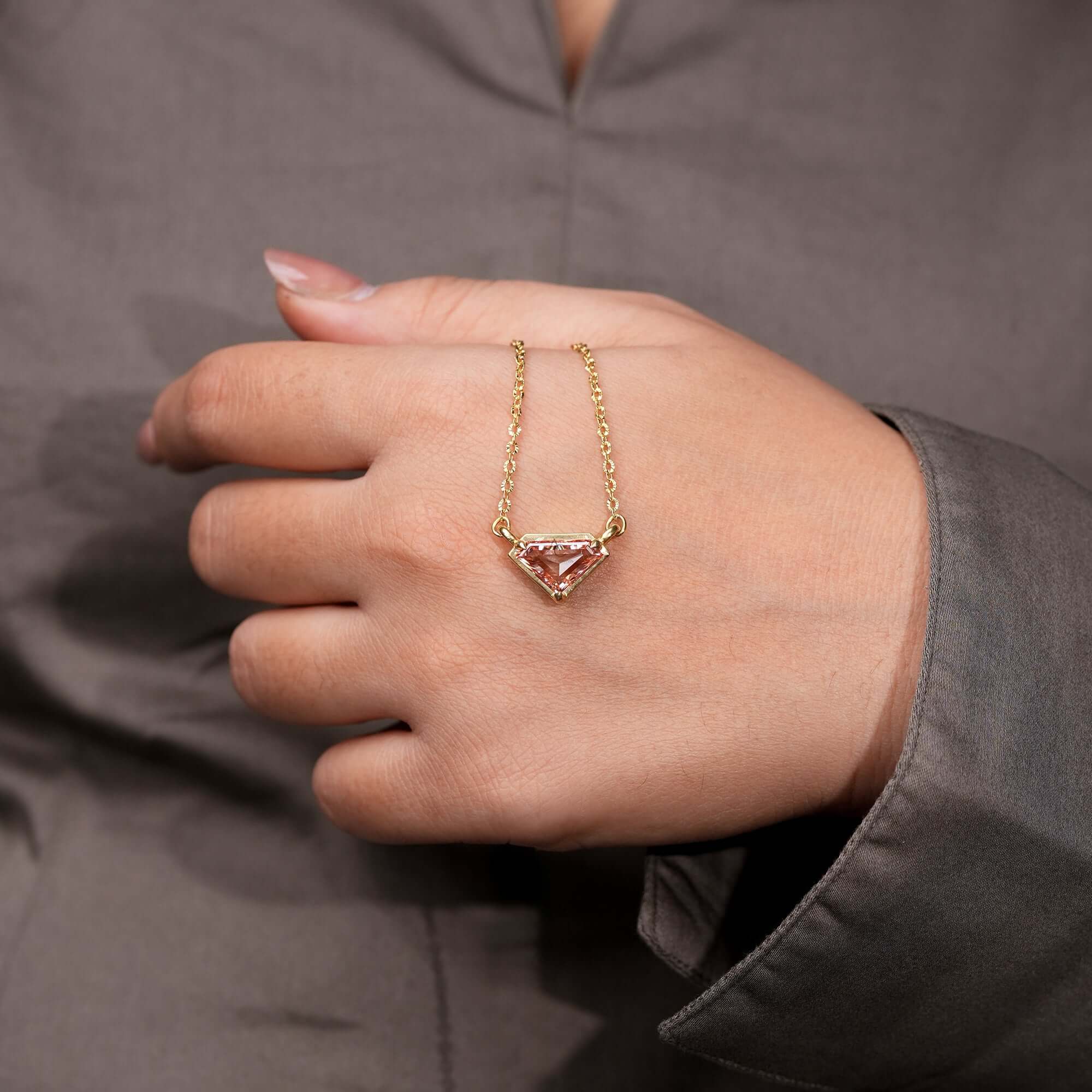 An exquisite gold chain necklace set with a pink geometric gemstone pendant, blending modern artistry with timeless sophistication.