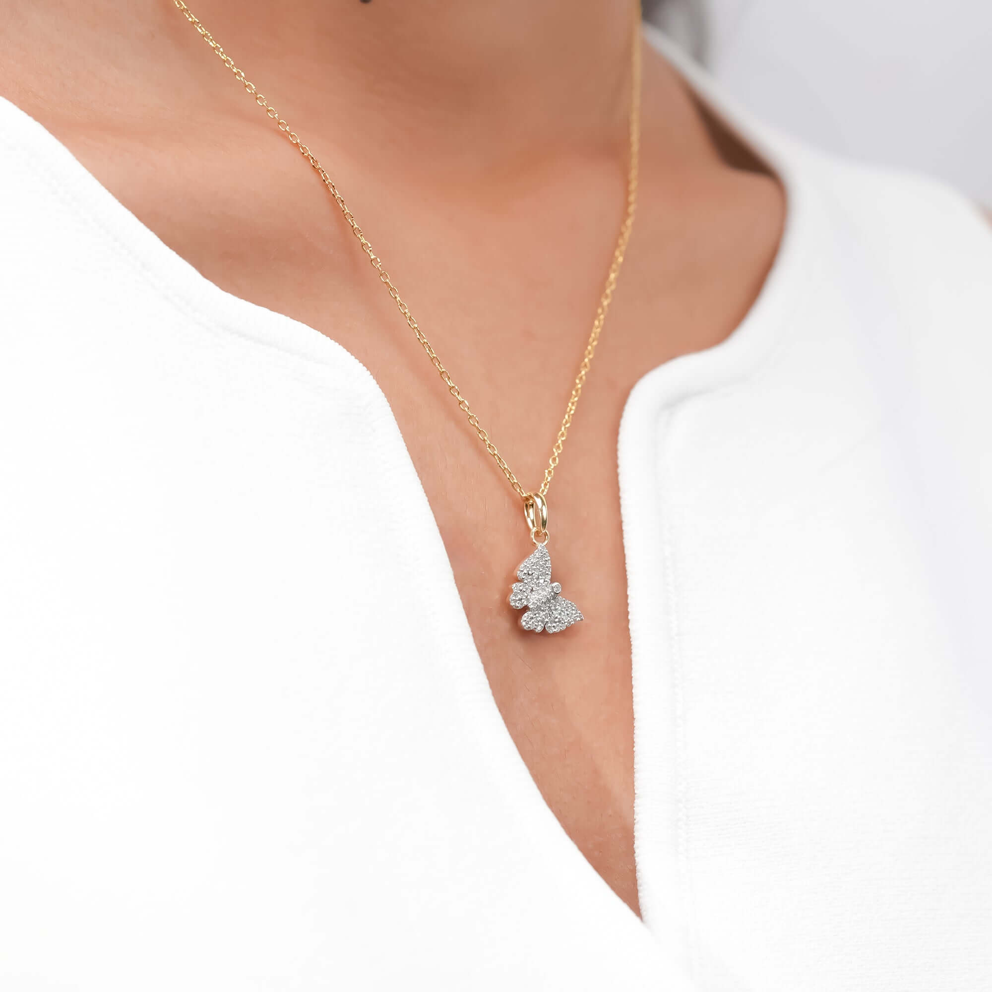 A sparkling butterfly pendant hangs from a fine gold chain, representing transformation, beauty, and lightness.