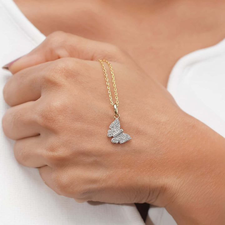A delicate gold necklace with a diamond butterfly pendant, elegantly, refined aesthetic.