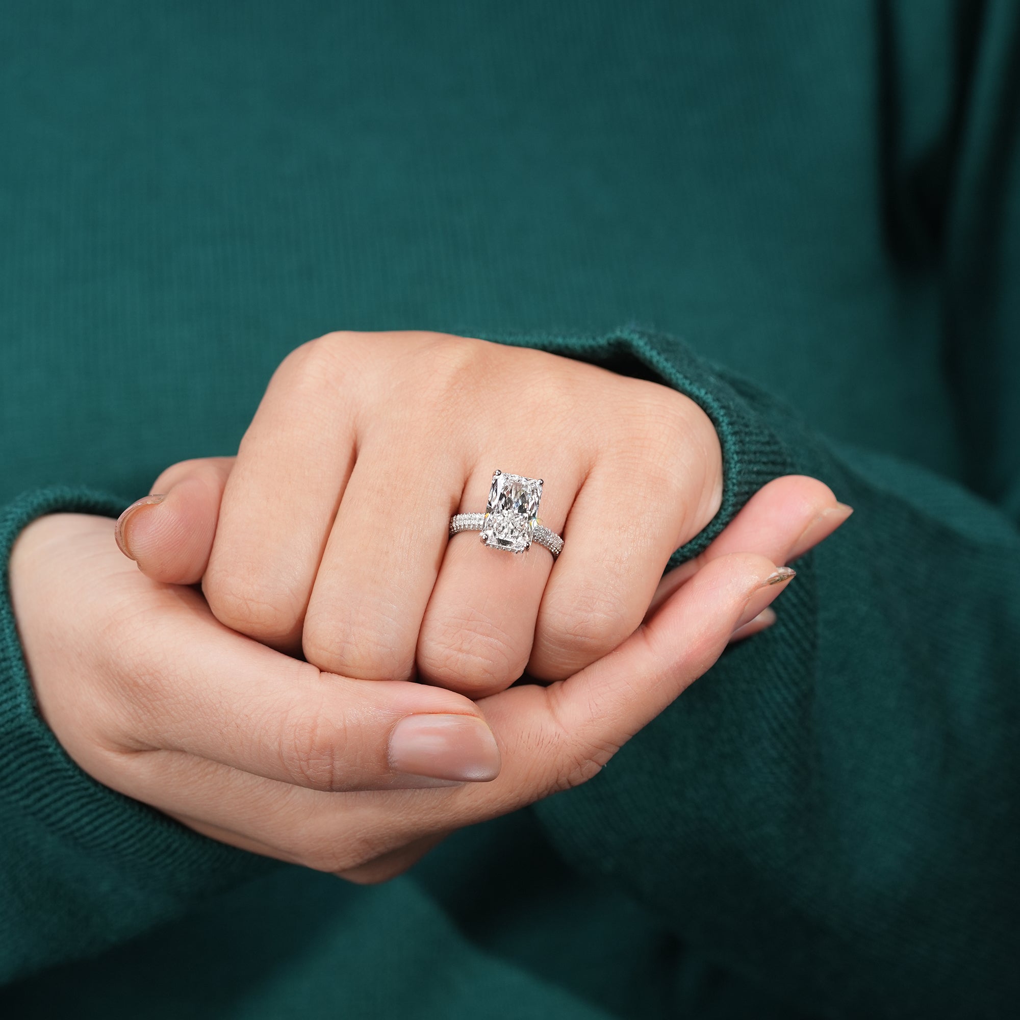 An exquisite radiant-cut diamond engagement ring crafted in platinum, featuring a wide pavé band that enhances the brilliance and grandeur of the central stone.
