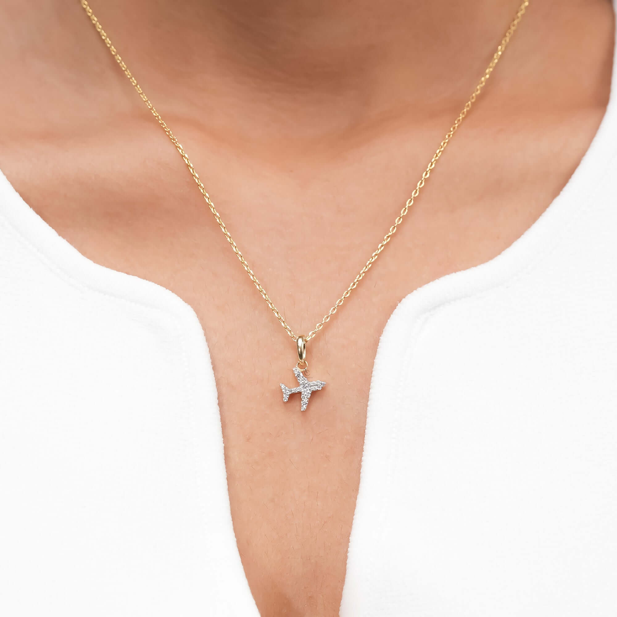 A minimalist gold necklace with a sparkling airplane pendant, symbolizing adventure and elegance in a refined jewelry design.