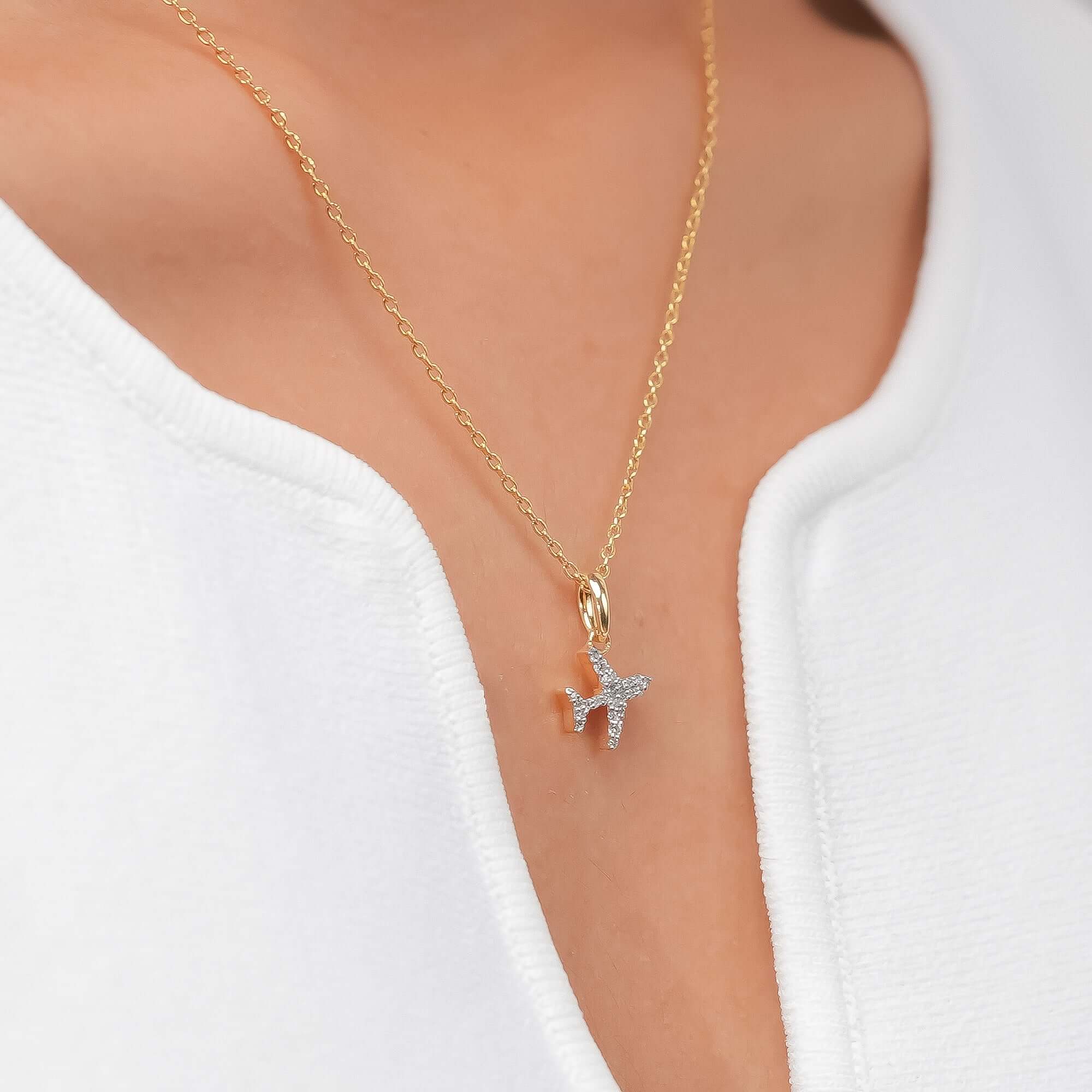 Simple gold chain necklace with a small diamond airplane pendant, modern look.