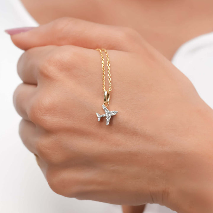 A stylish gold chain with a diamond-encrusted airplane charm, aspirational aesthetic.