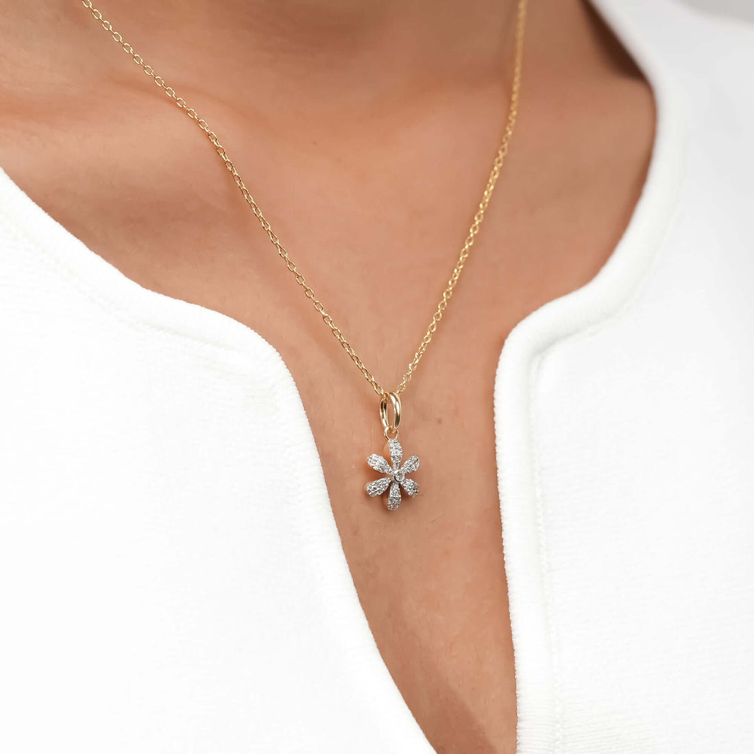 A dainty daisy pendant sparkles at the center of a gold chain, representing natural beauty and understated grace.