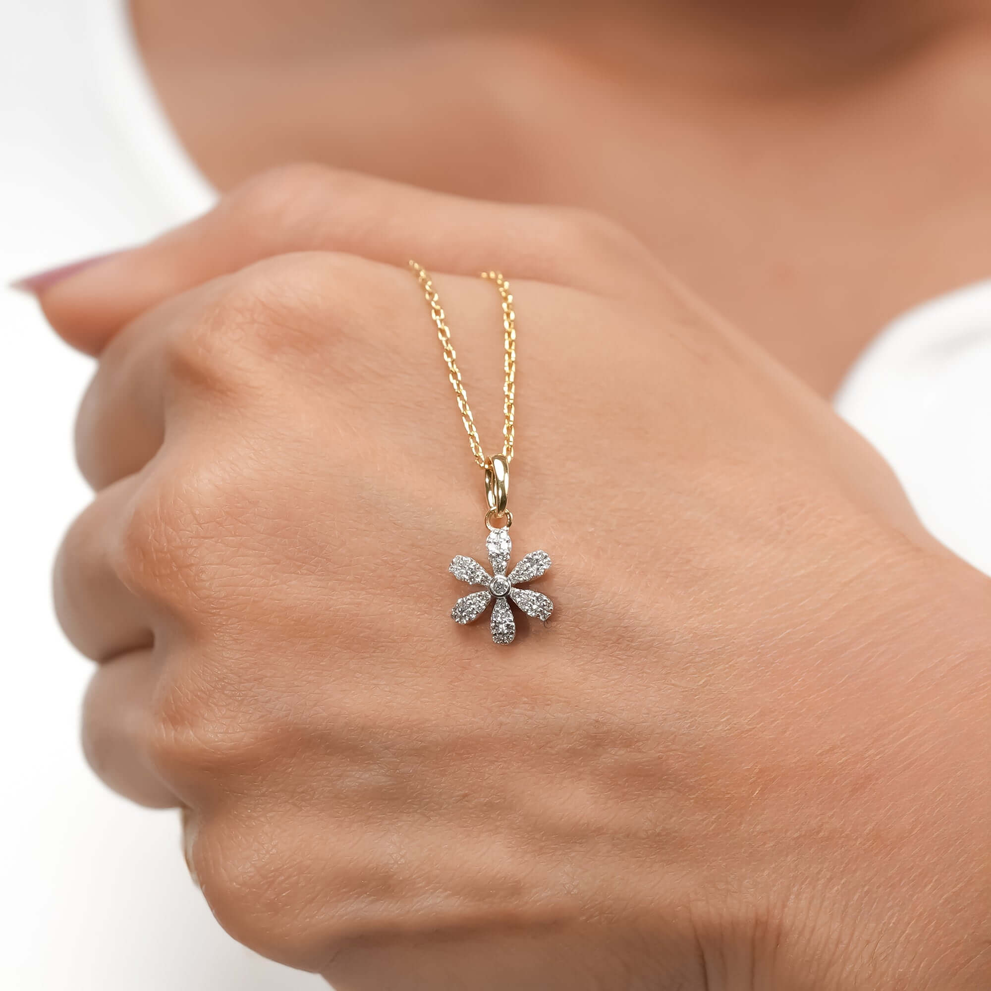 A chic gold necklace with a diamond-paved floral pendant, contemporary aesthetic.