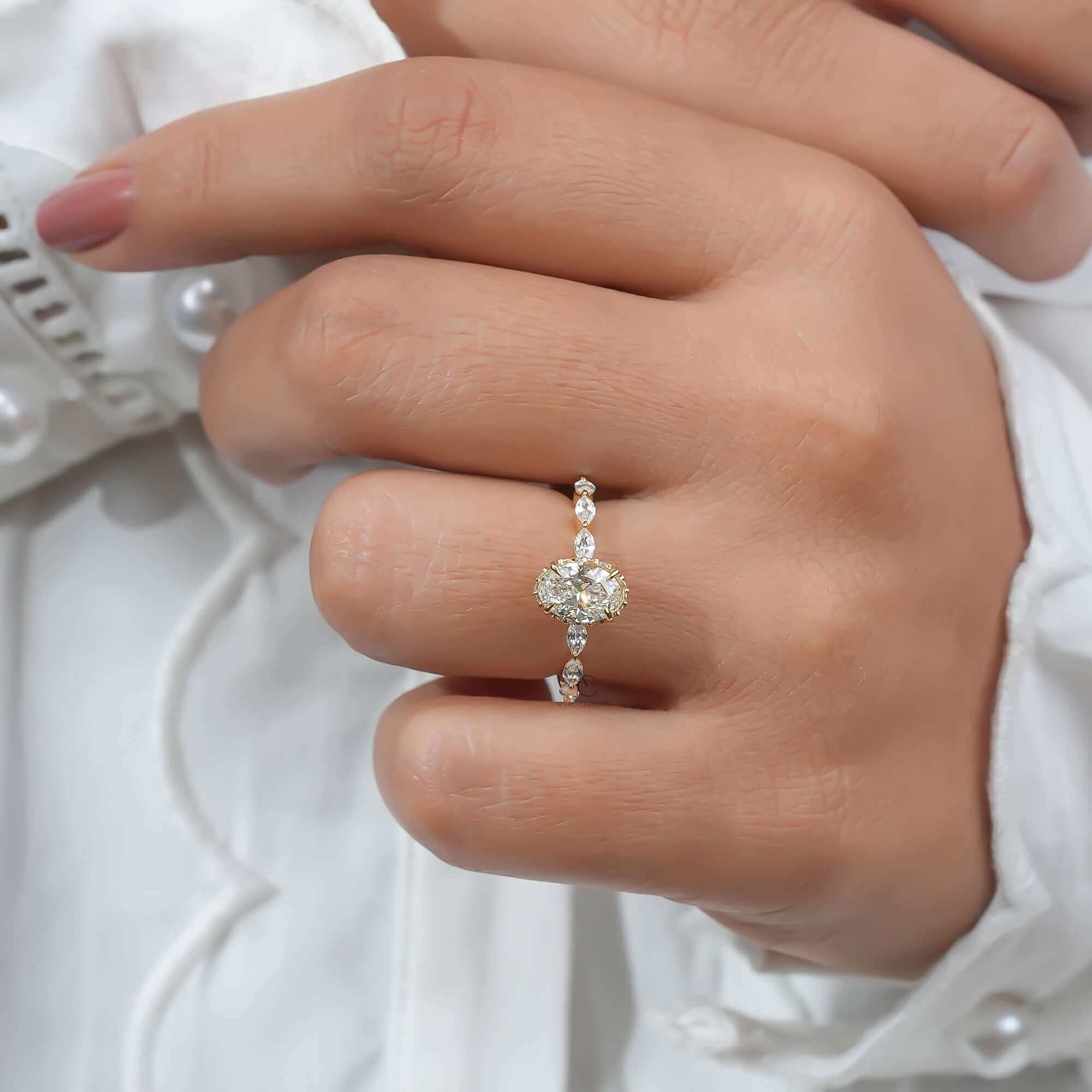 Oval diamond ring worn on finger with marquise side stones.