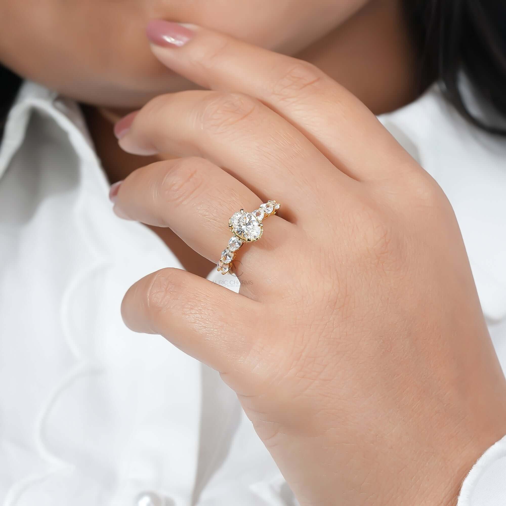 Oval diamond ring with side stones worn on finger, showing sparkle.