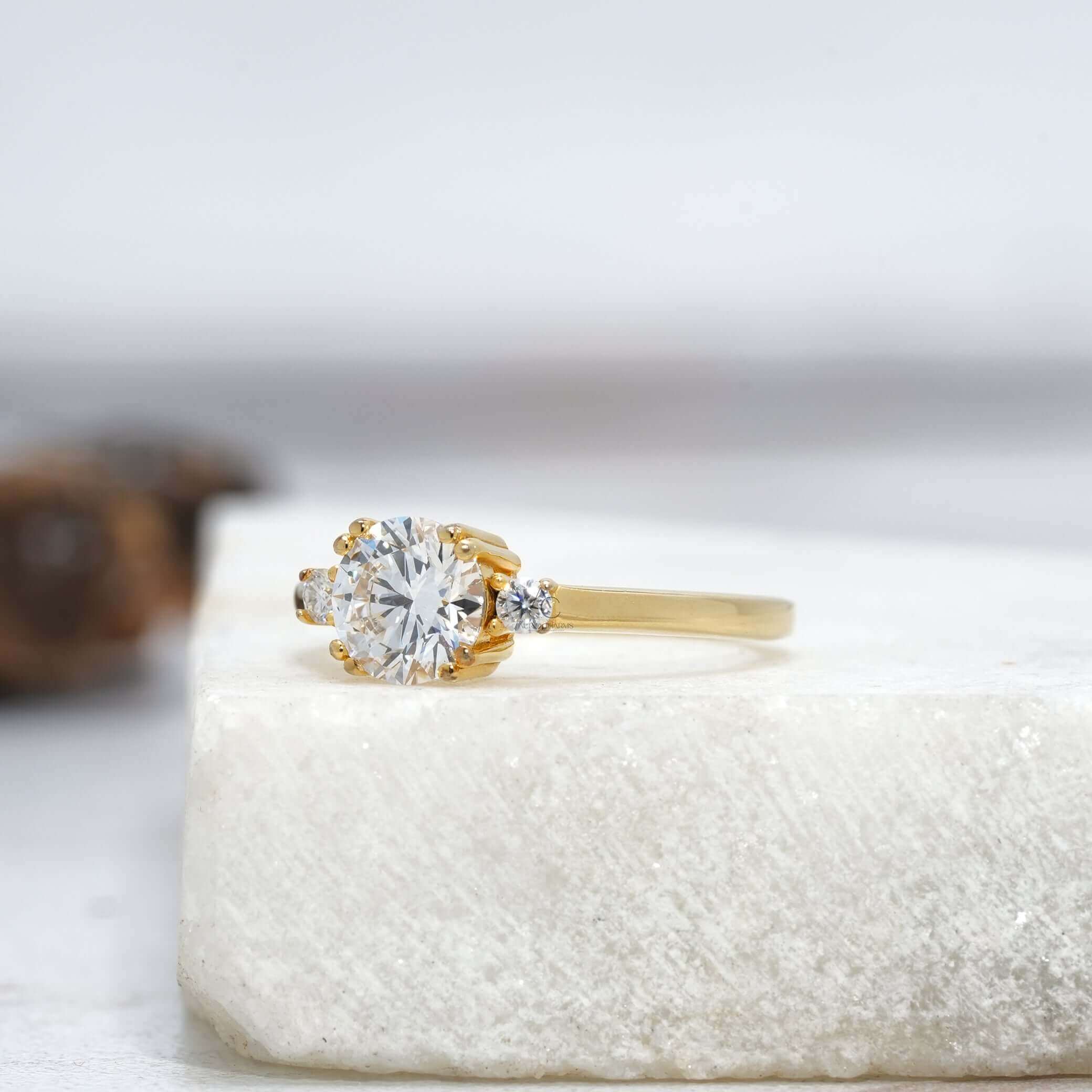 Angled view of a three-stone round diamond engagement ring showcasing intricate prong detailing and a smooth metal band.