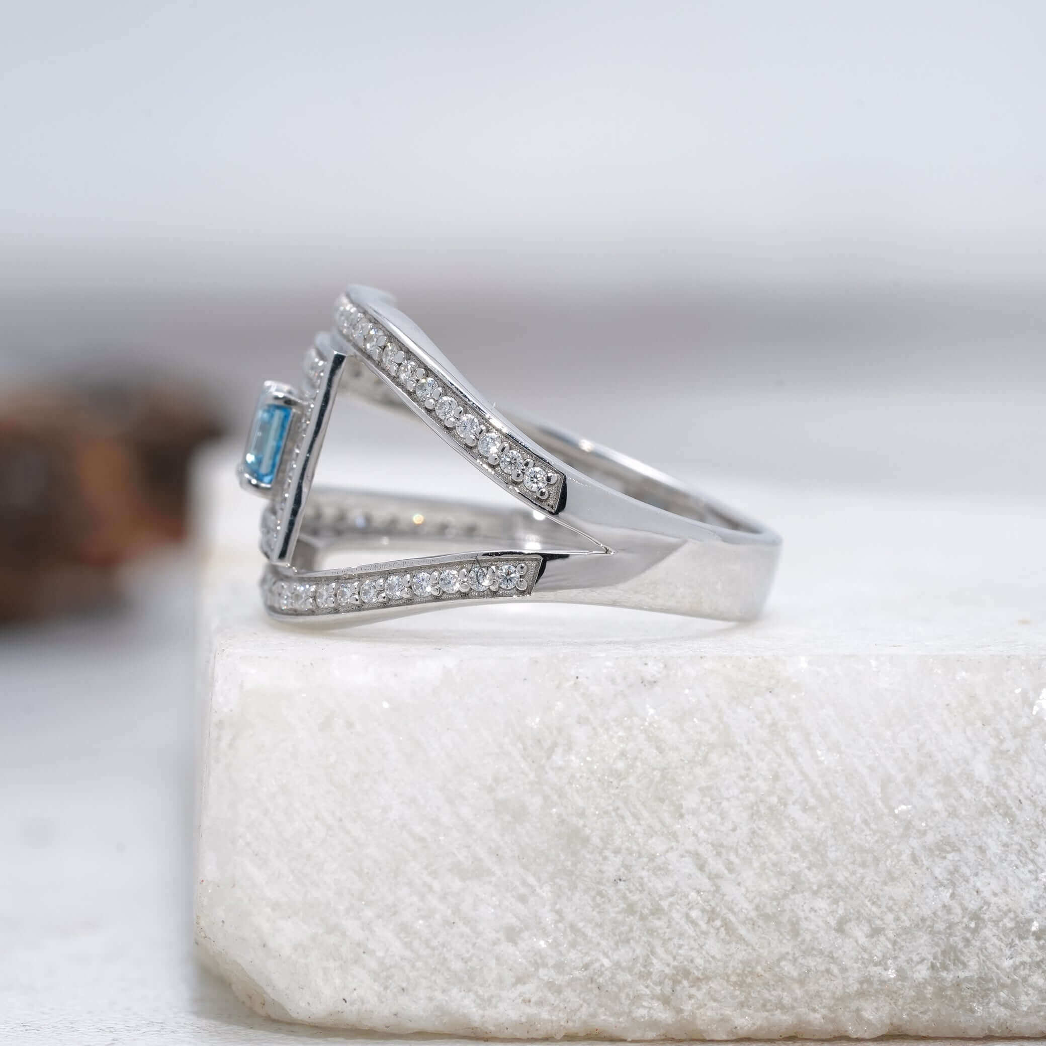 Angled side view of blue gemstone ring with split band and diamonds.