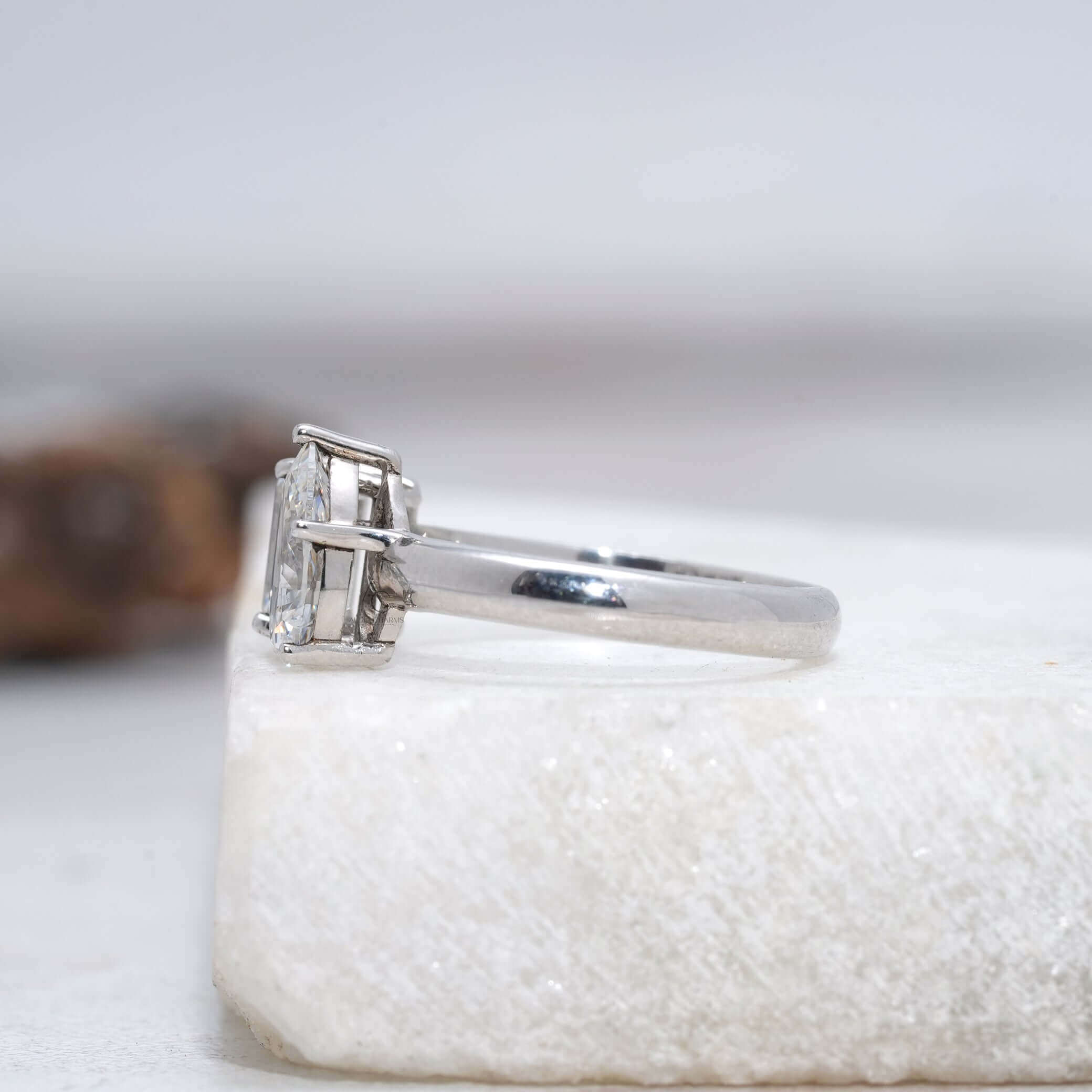 Side view of emerald and pear-cut Toi et Moi lab-grown diamond wedding ring.