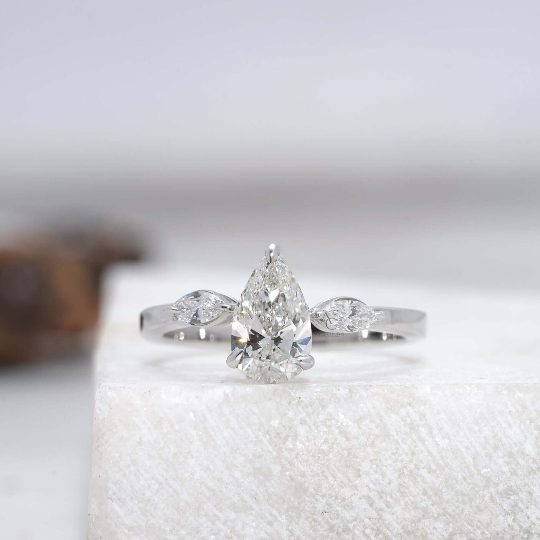 front view Pear diamond ring with side marquise stones and a sleek metal band.