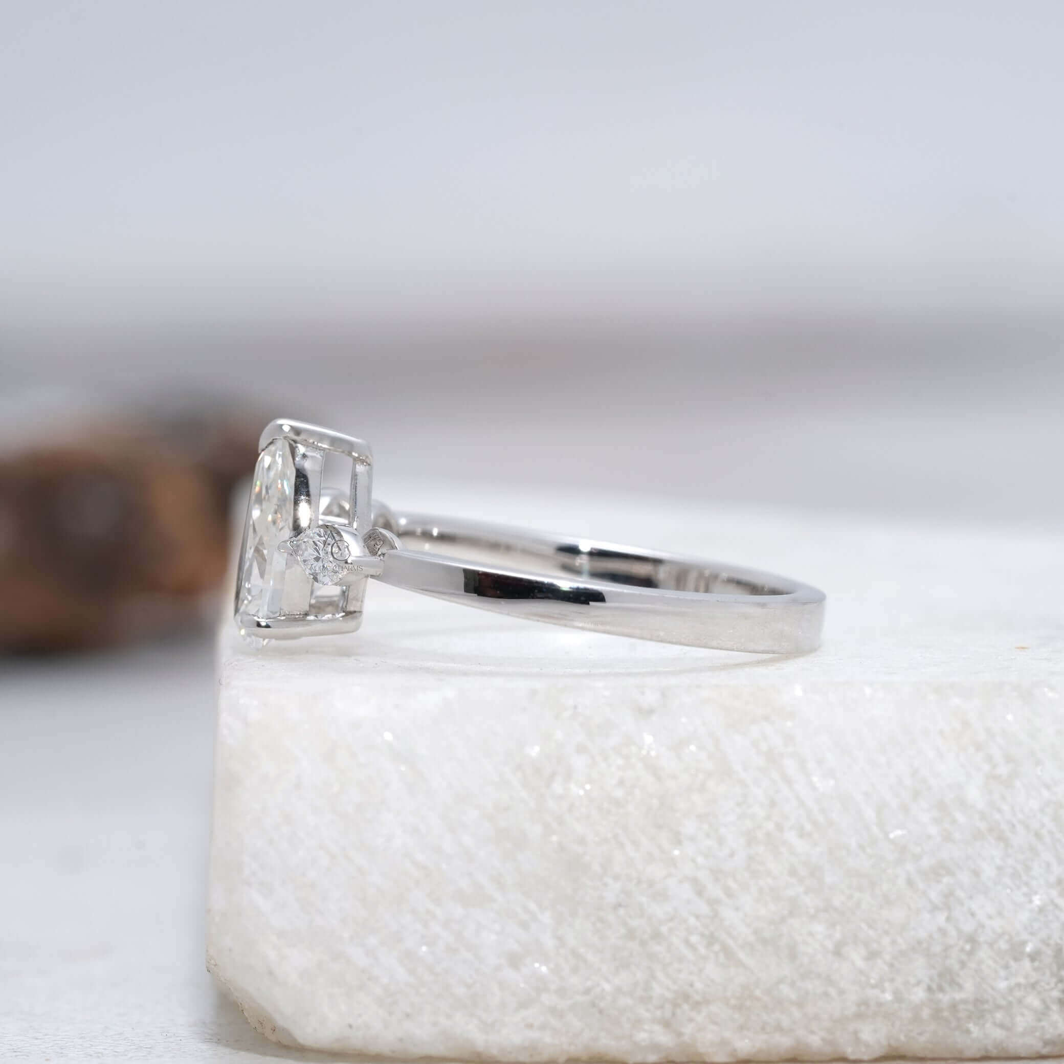 side view of a pear-shaped diamond ring with intricate metalwork details.