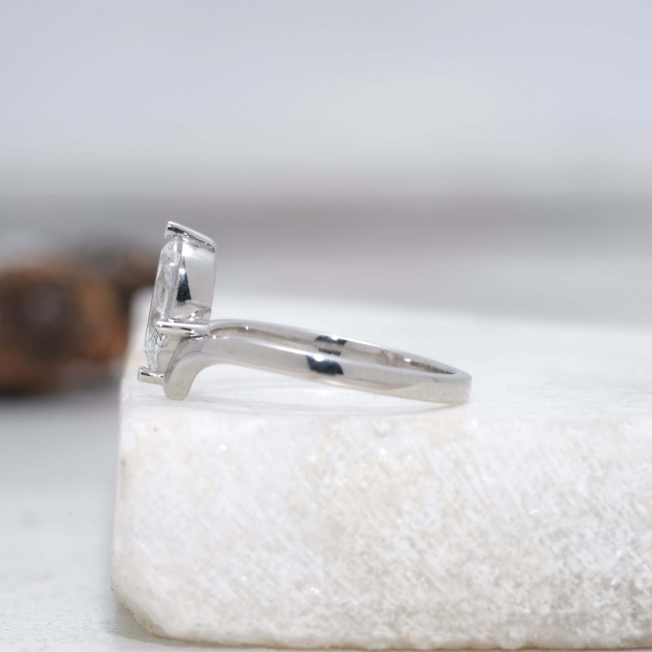 Side view of a pear-cut diamond engagement ring on a sleek V-shaped band, highlighting its stunning craftsmanship.