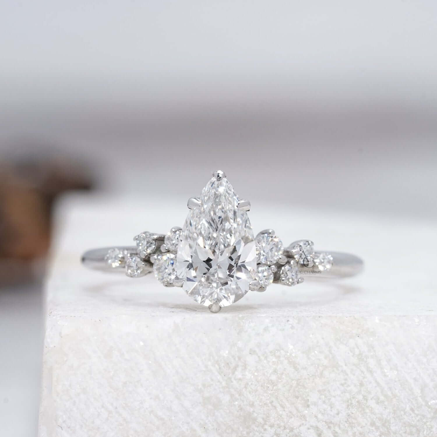 Pear-cut diamond ring with delicate side stones, elegantly displayed with its reflection.