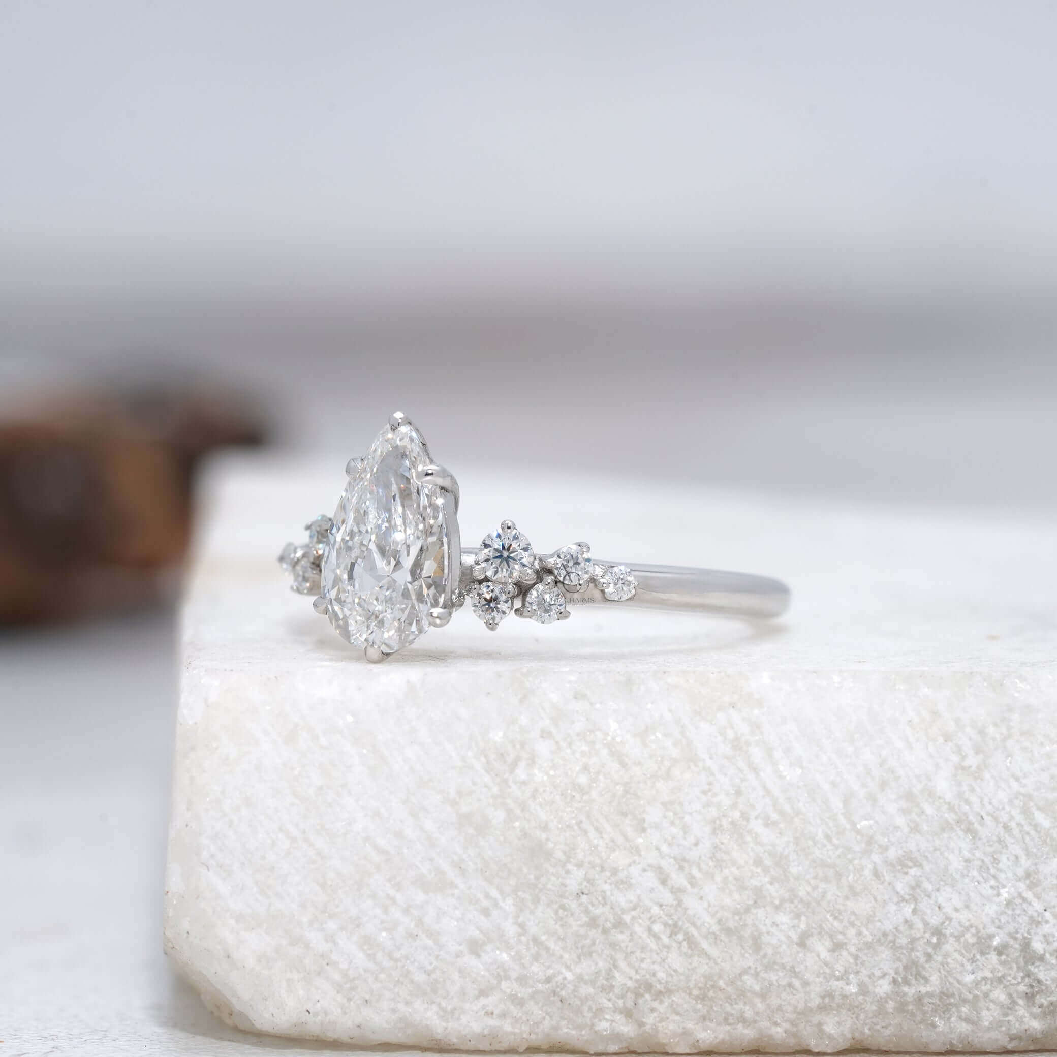 Side view of a pear-cut diamond ring with intricate detailing and sparkling accents.