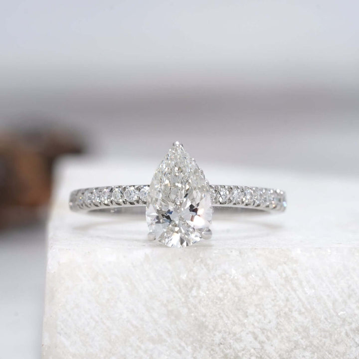 Pear-cut diamond ring with a shimmering halo and delicate diamond band.