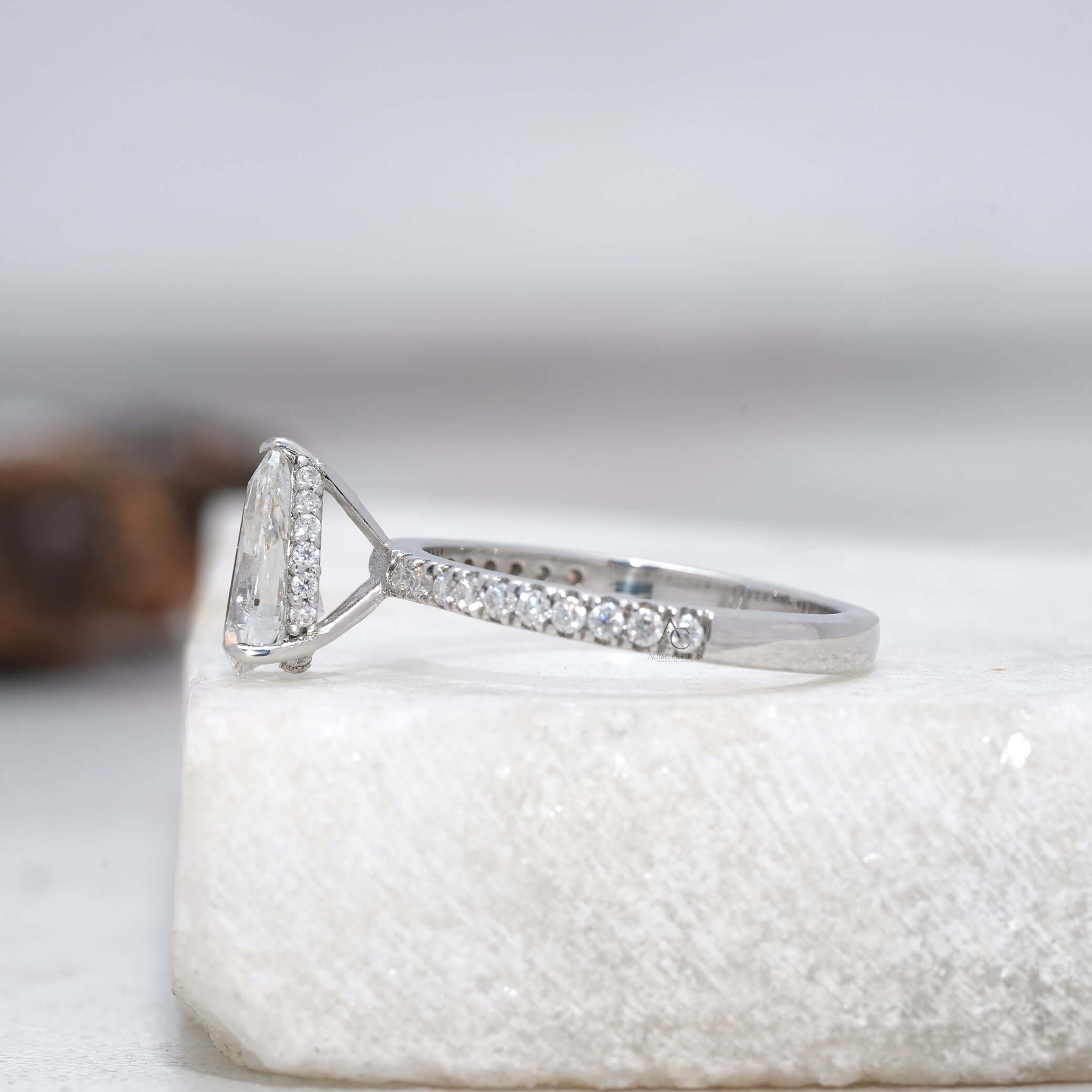 Side profile of a pear-cut diamond ring featuring a sparkling halo setting.