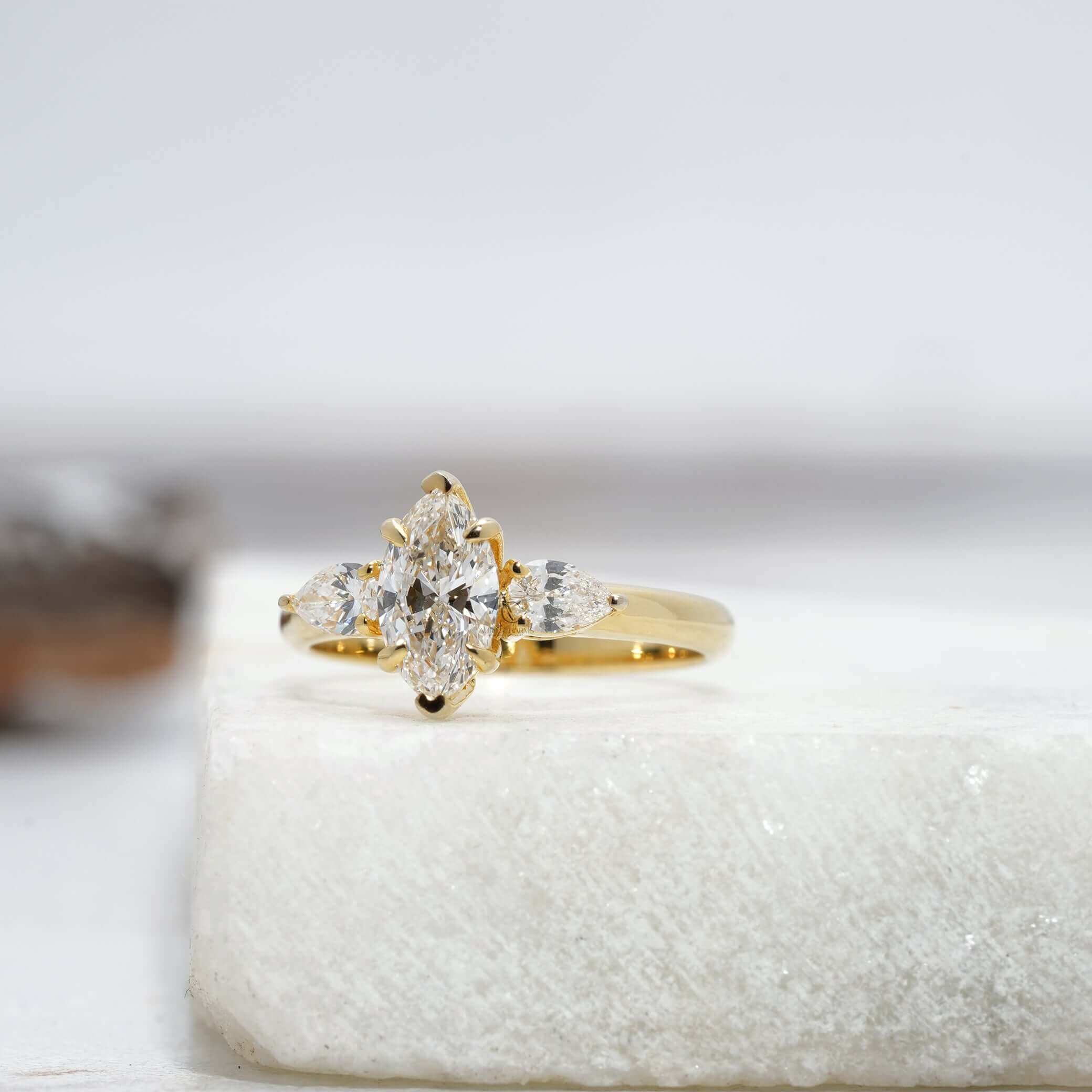 Angled view of marquise diamond ring showing pear-cut accents and sleek metal band design.