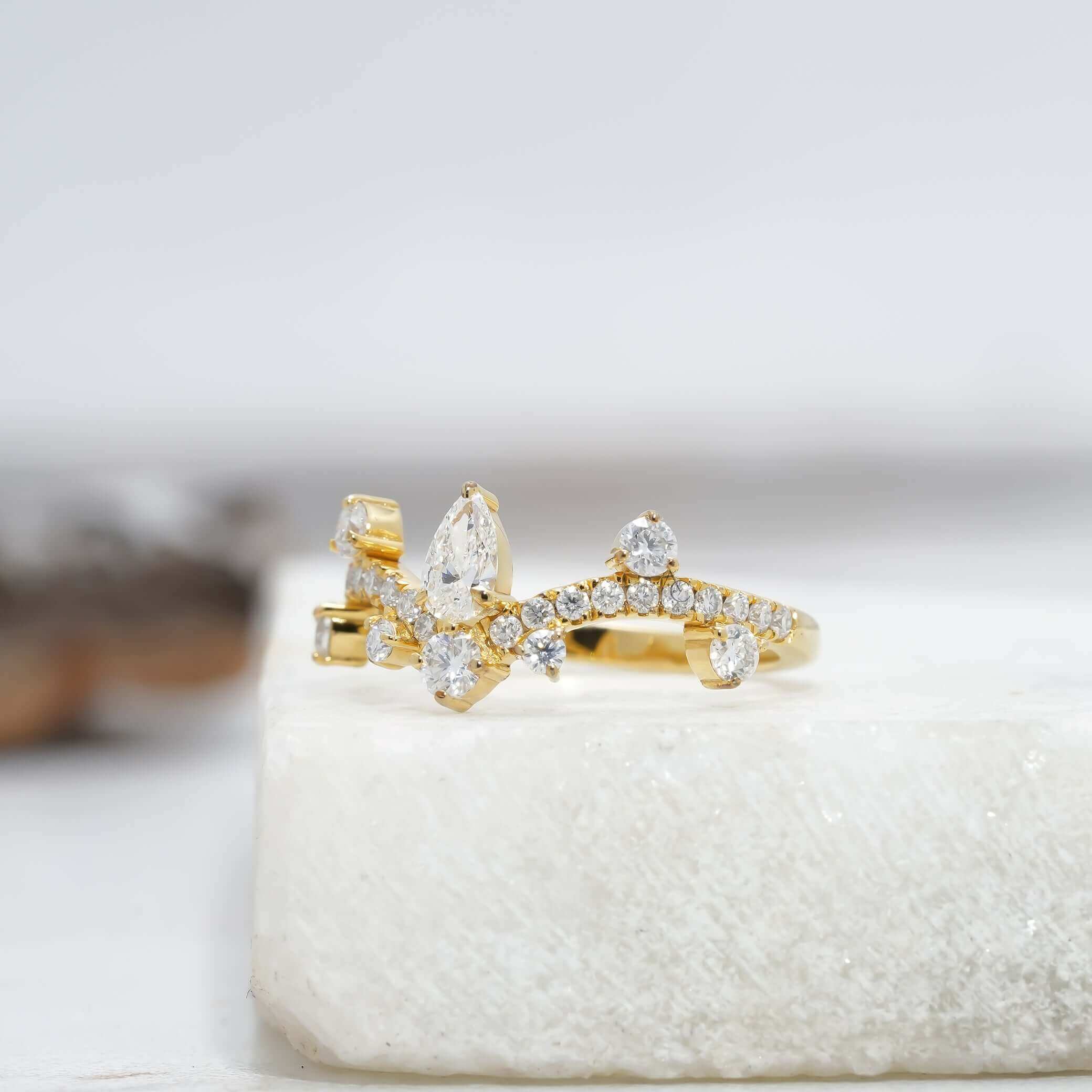 Side profile of a pear-shaped diamond crown ring featuring intricate detailing and a radiant shine.