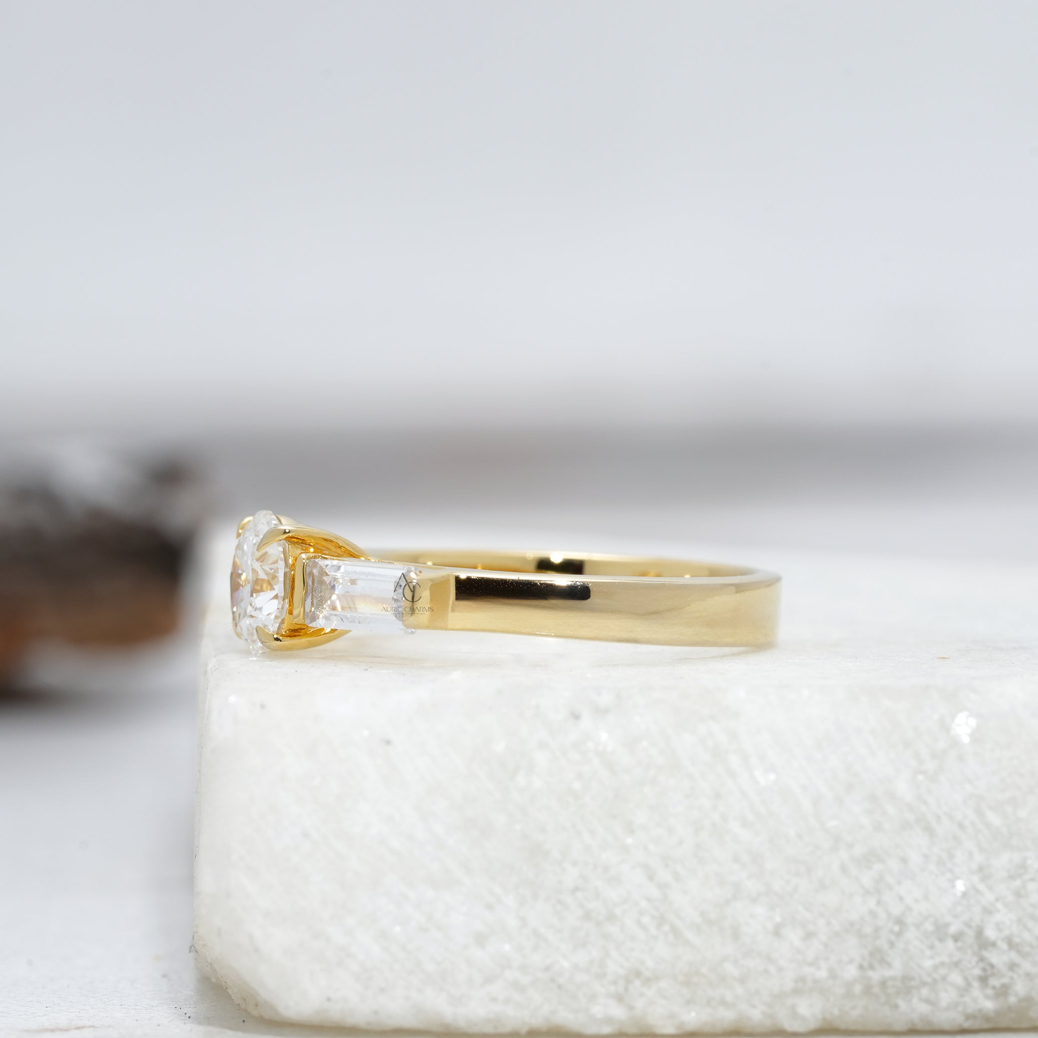 side view of a round diamond ring with sparkling baguette-cut side stones on a polished platinum setting.