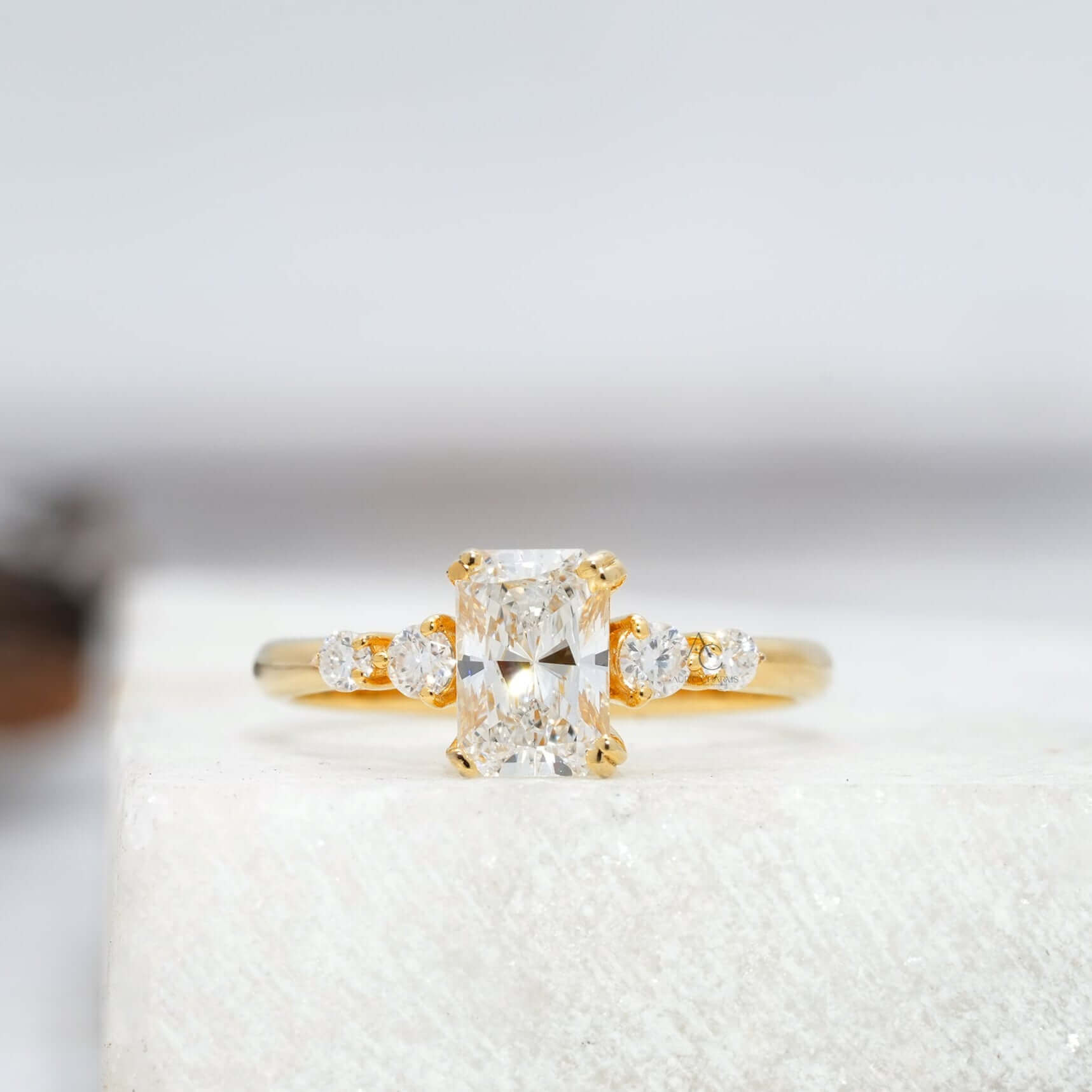 Radiant-cut diamond engagement ring with side stones on a sleek white gold band.
