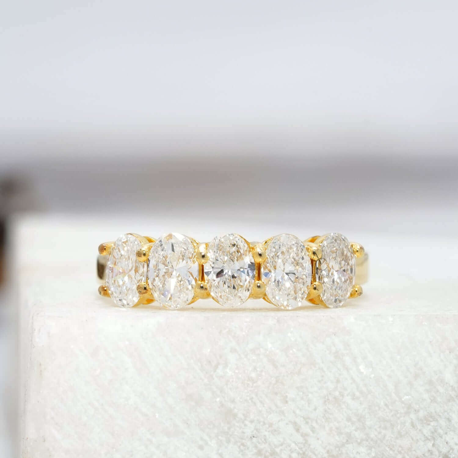 Front view of an elegant lab-grown diamond band with five oval-cut diamonds in white gold.