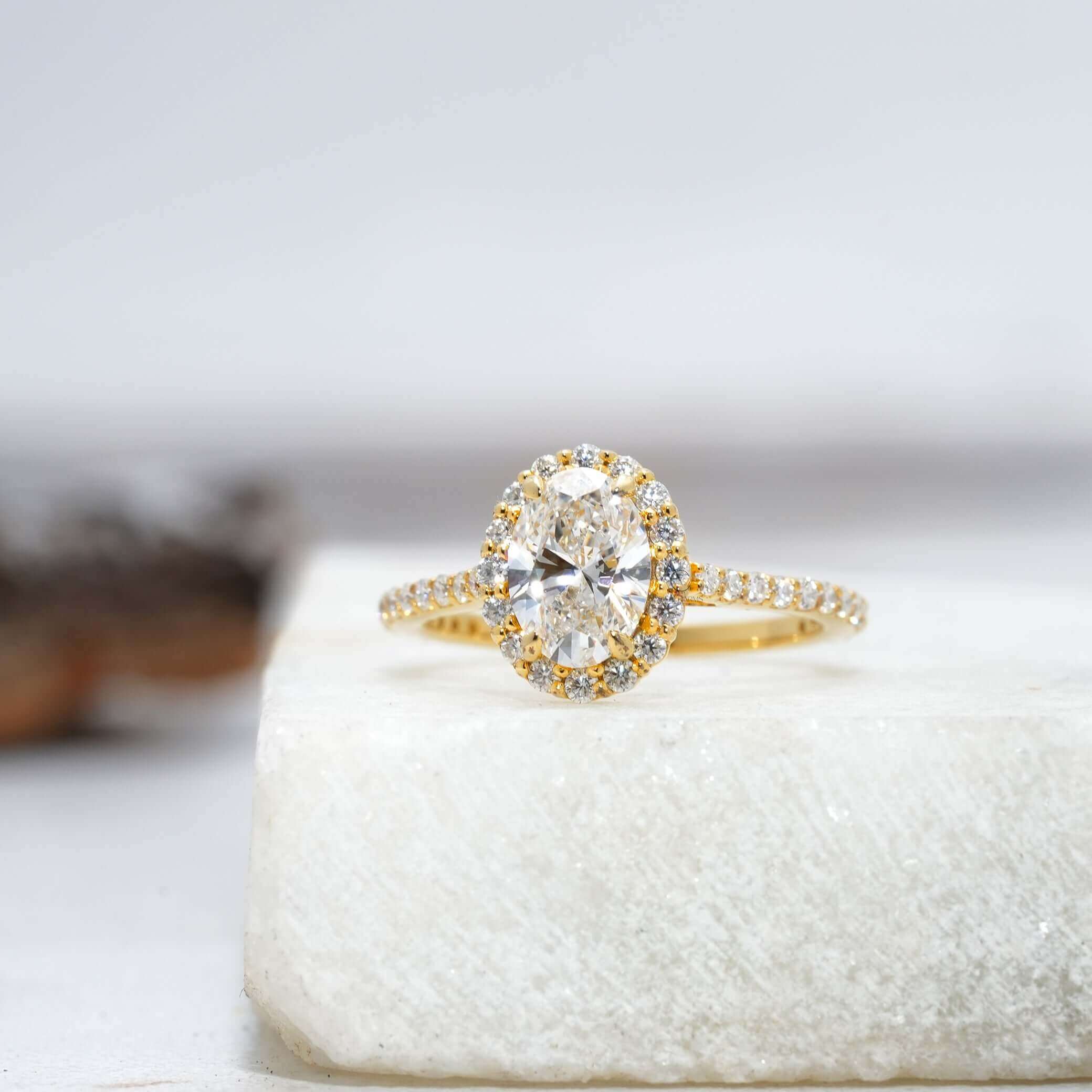 detailed view of an oval-cut diamond ring with halo design and sparkling pavé band.