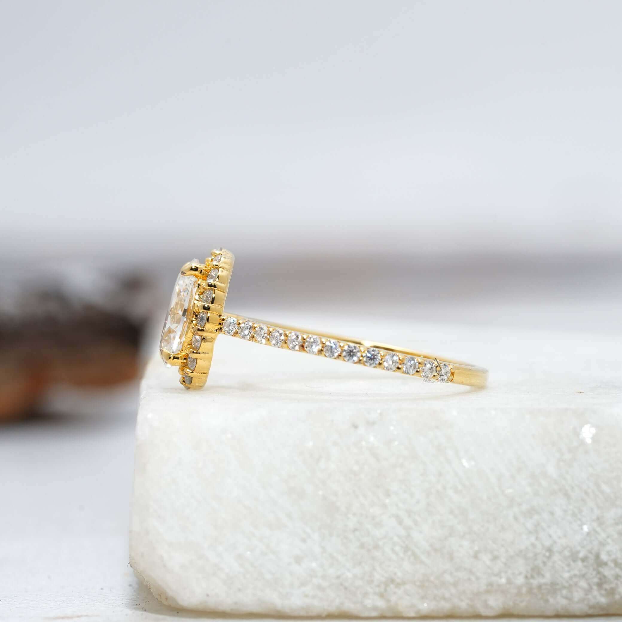 Profile view of an oval-cut diamond ring with a halo setting and intricate band details.