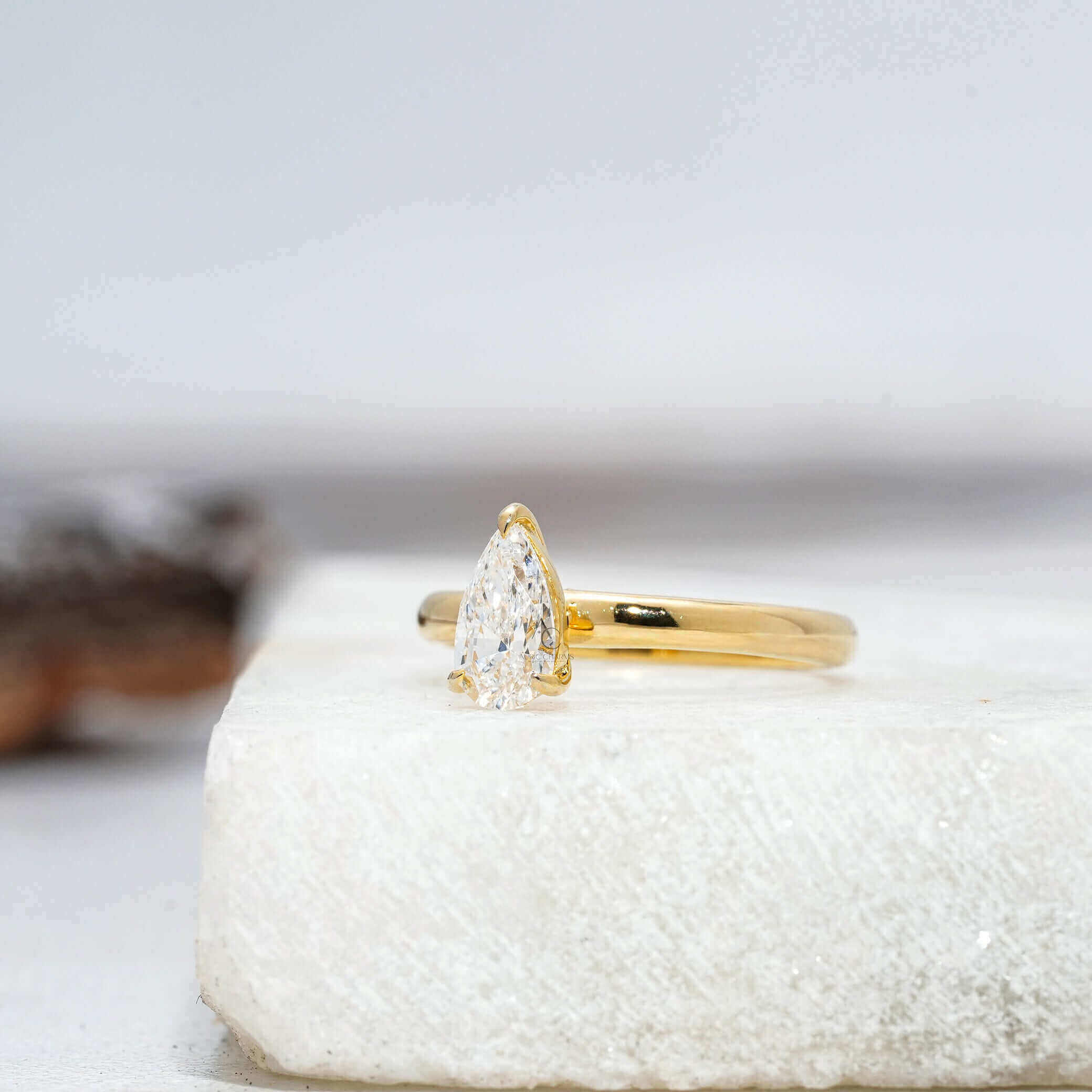 Side view of a pear-cut lab-grown diamond solitaire ring showcasing its stunning facets and high-quality craftsmanship on a polished platinum band.