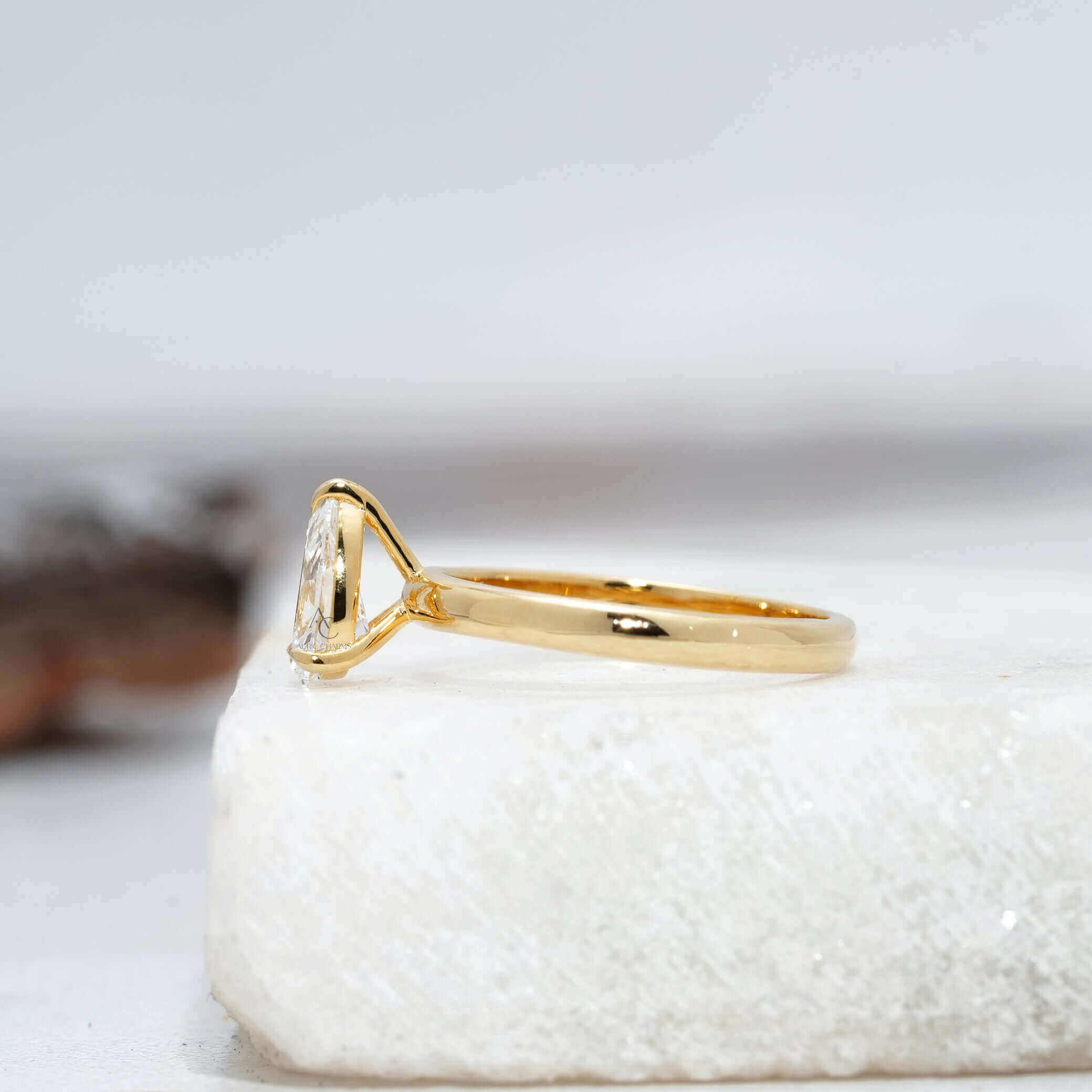 Angled view of a pear-cut lab-grown diamond solitaire ring highlighting the unique setting and attention to detail, set against a minimalist reflective background